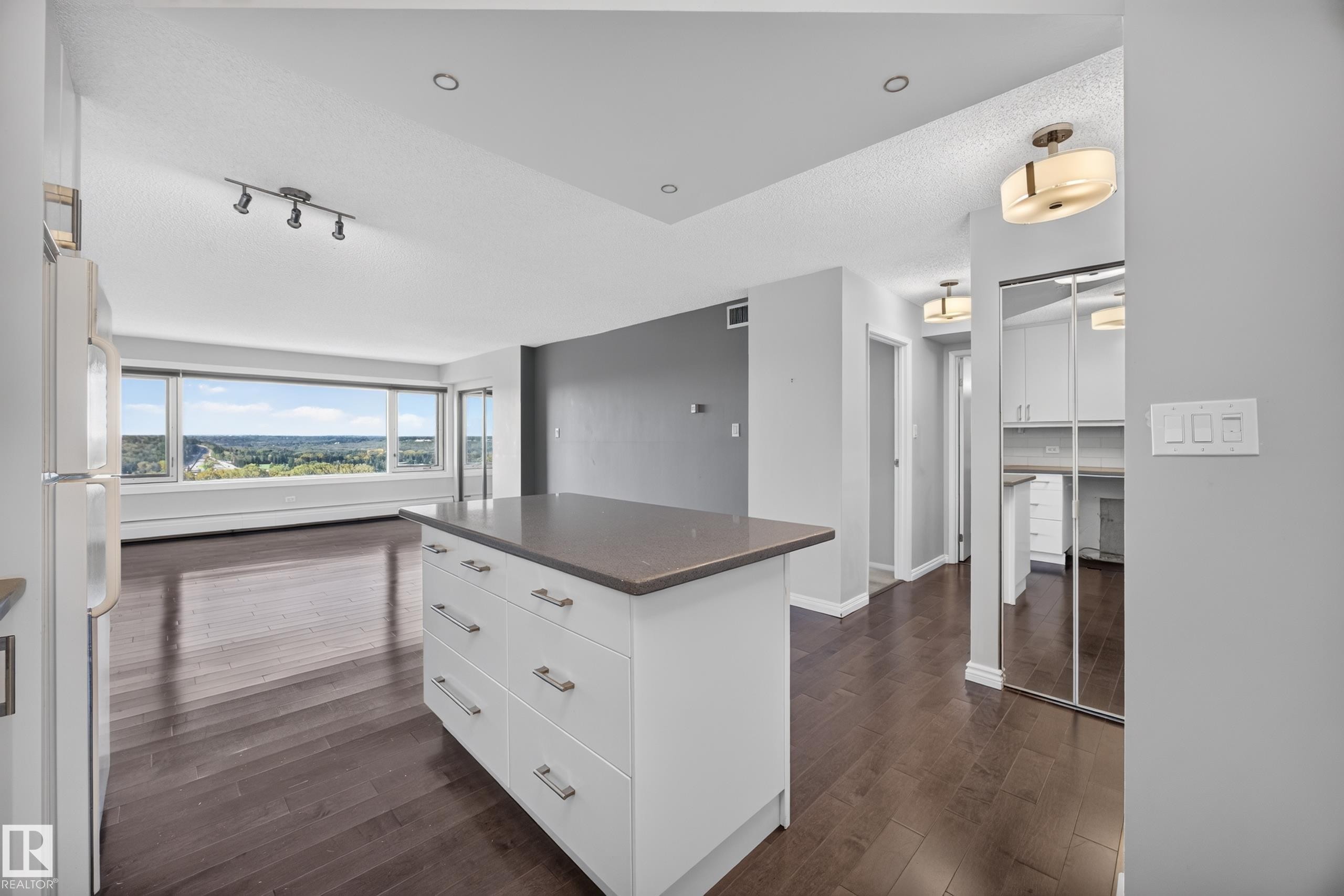 White kitchen featuring quartz counters, hardwood flooring, electric stove, microwave hood fan, space for a dishwasher, and refrigerator. - #803 10011 123 St Nw, Edmonton, AB