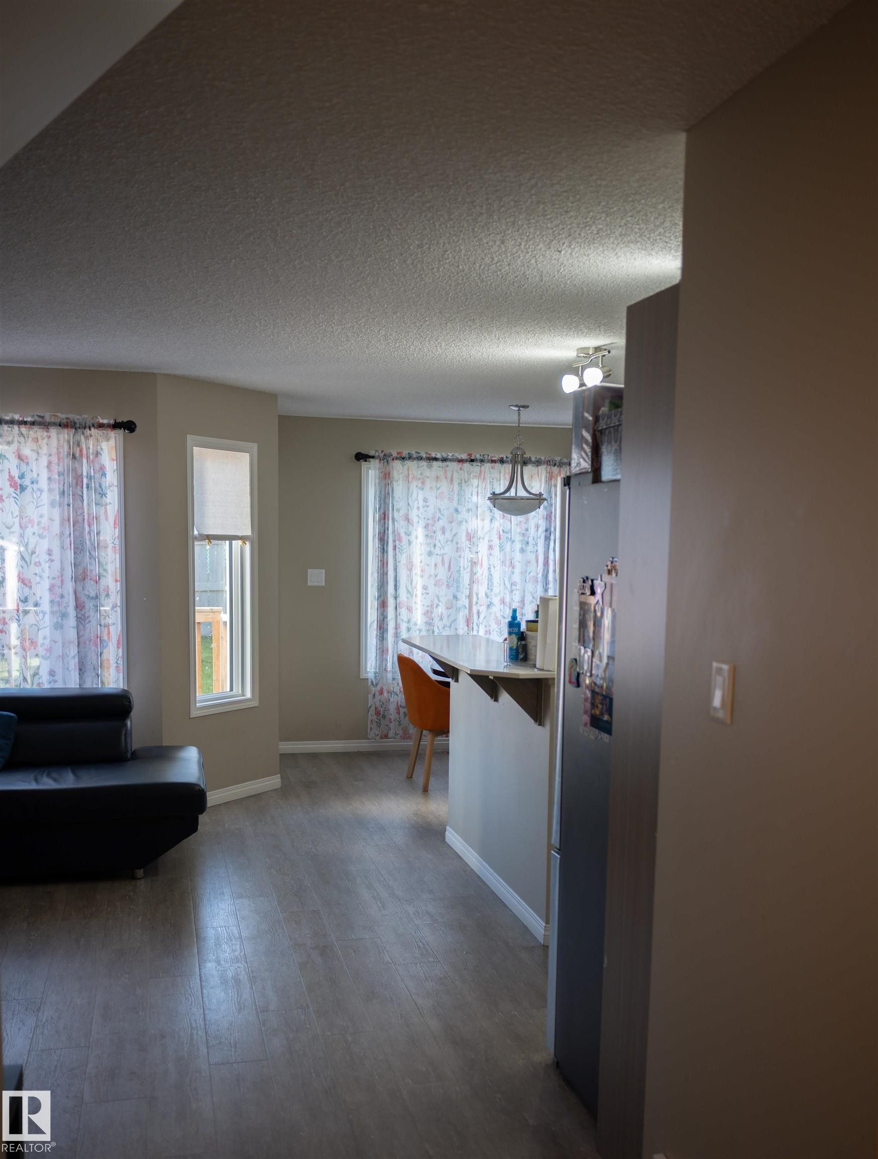 Wood-finish flooring throughout, bay windows, built-in breakfast bar, and a contemporary chandelier - 9014 Cooper Link Link Sw, Edmonton, AB