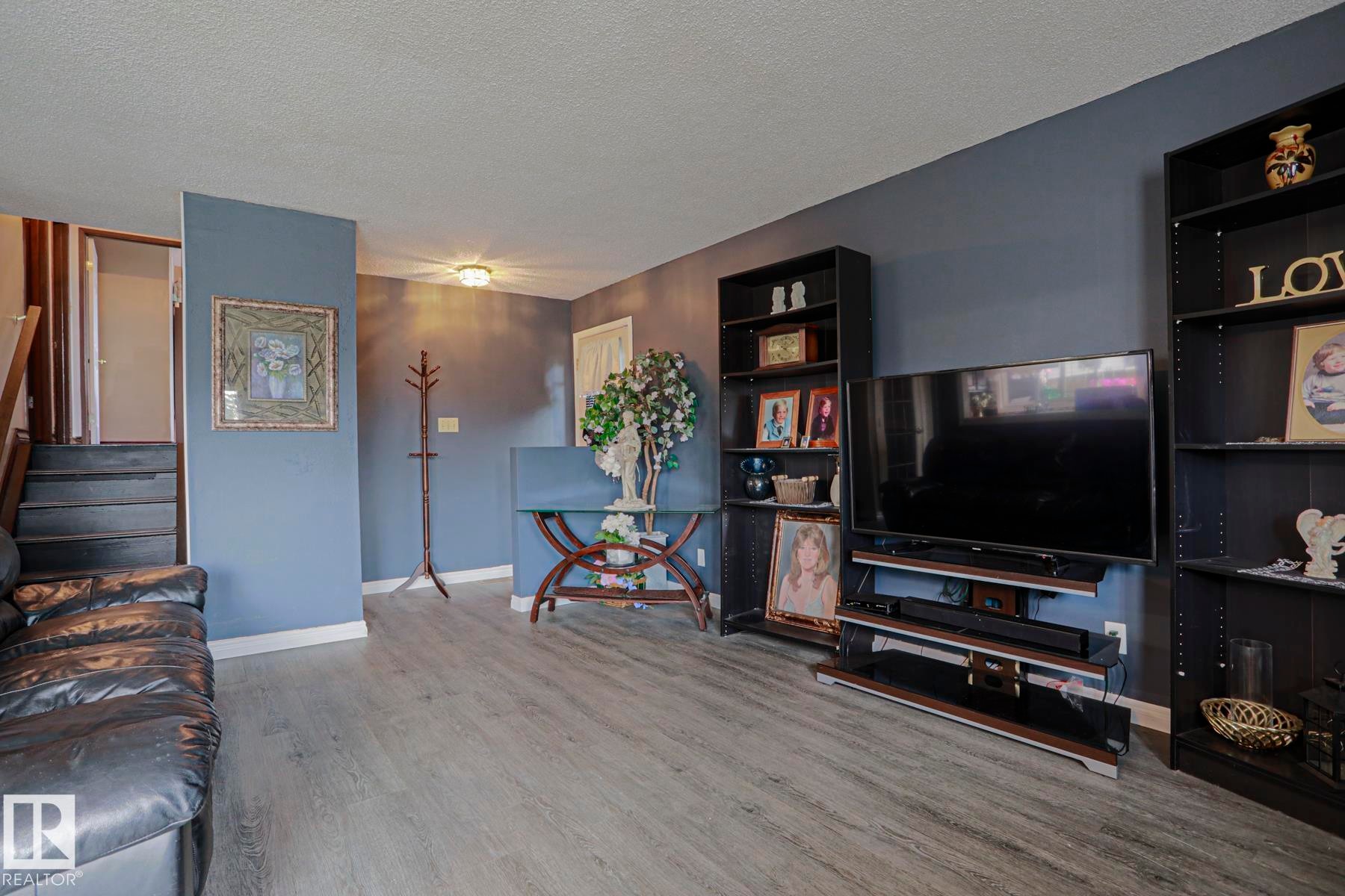 Wood-finish flooring, staircase with dark treads, light-toned ceiling, and built-in shelving units - 11440 144 Avenue Nw, Edmonton, AB