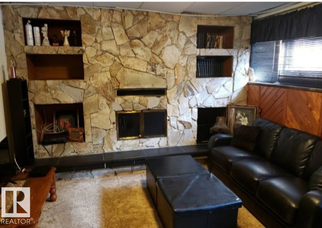 Stone accent wall with built-in shelving, dual fireplaces, and paneled wainscoting - 11440 144 Avenue Nw, Edmonton, AB