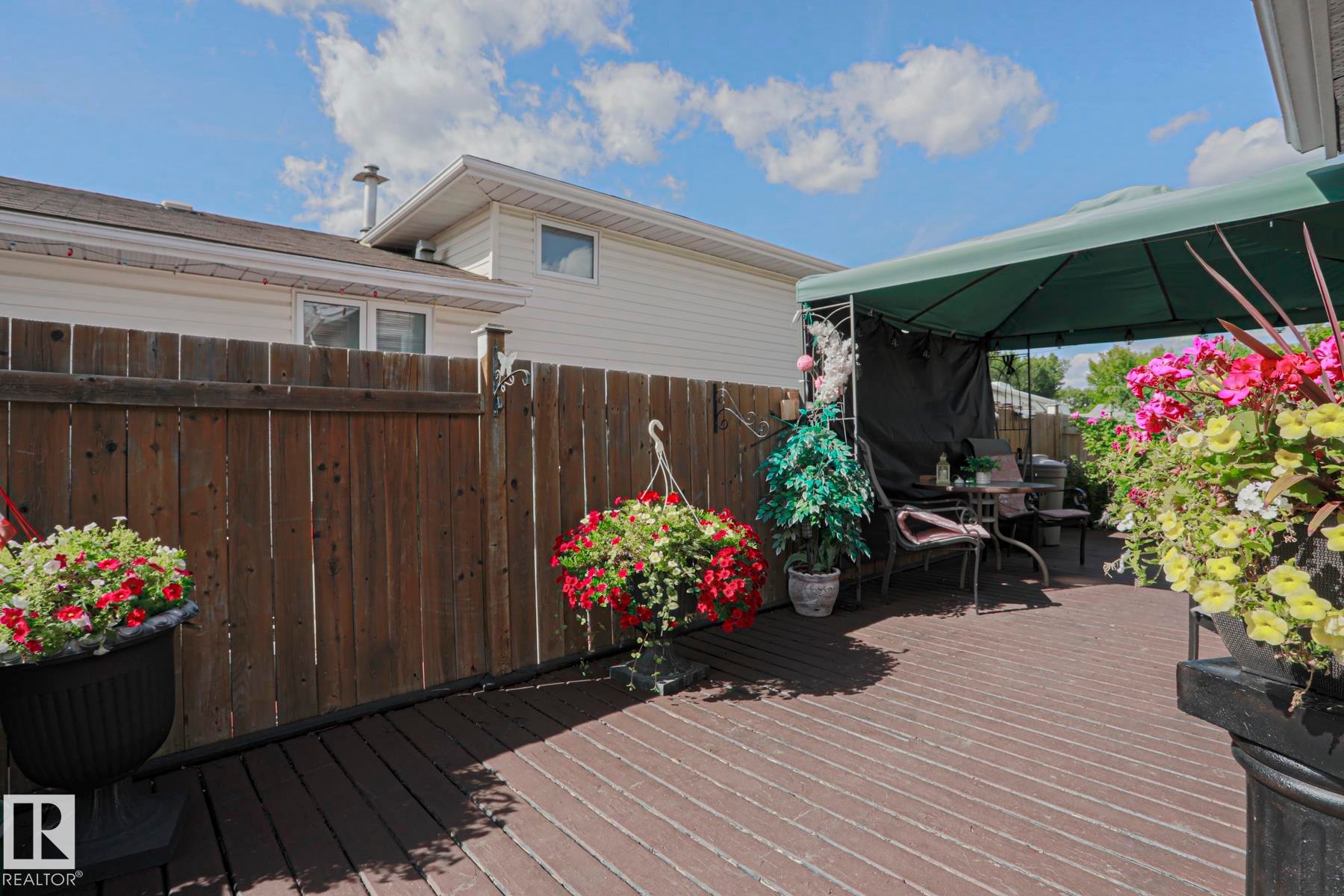 Wood-finish deck with a privacy fence and a green canopy - 11440 144 Avenue Nw, Edmonton, AB