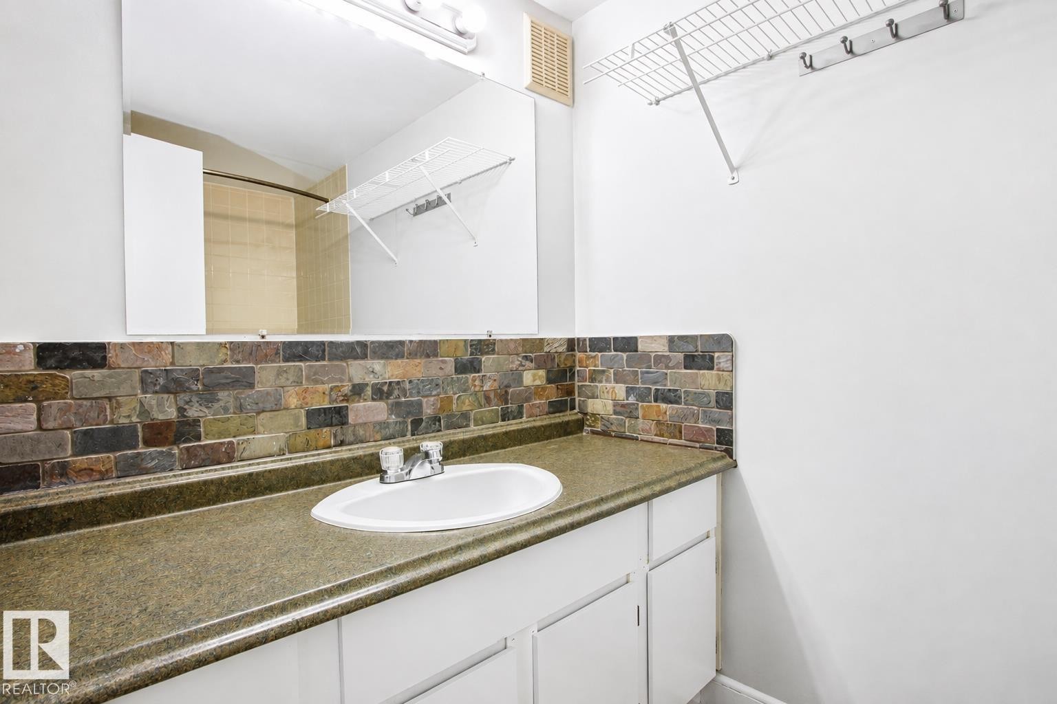 Vanity with integrated sink, stone-look countertop, and brick-patterned backsplash - #203 2624 Mill Woods Rd E Nw, Edmonton, AB