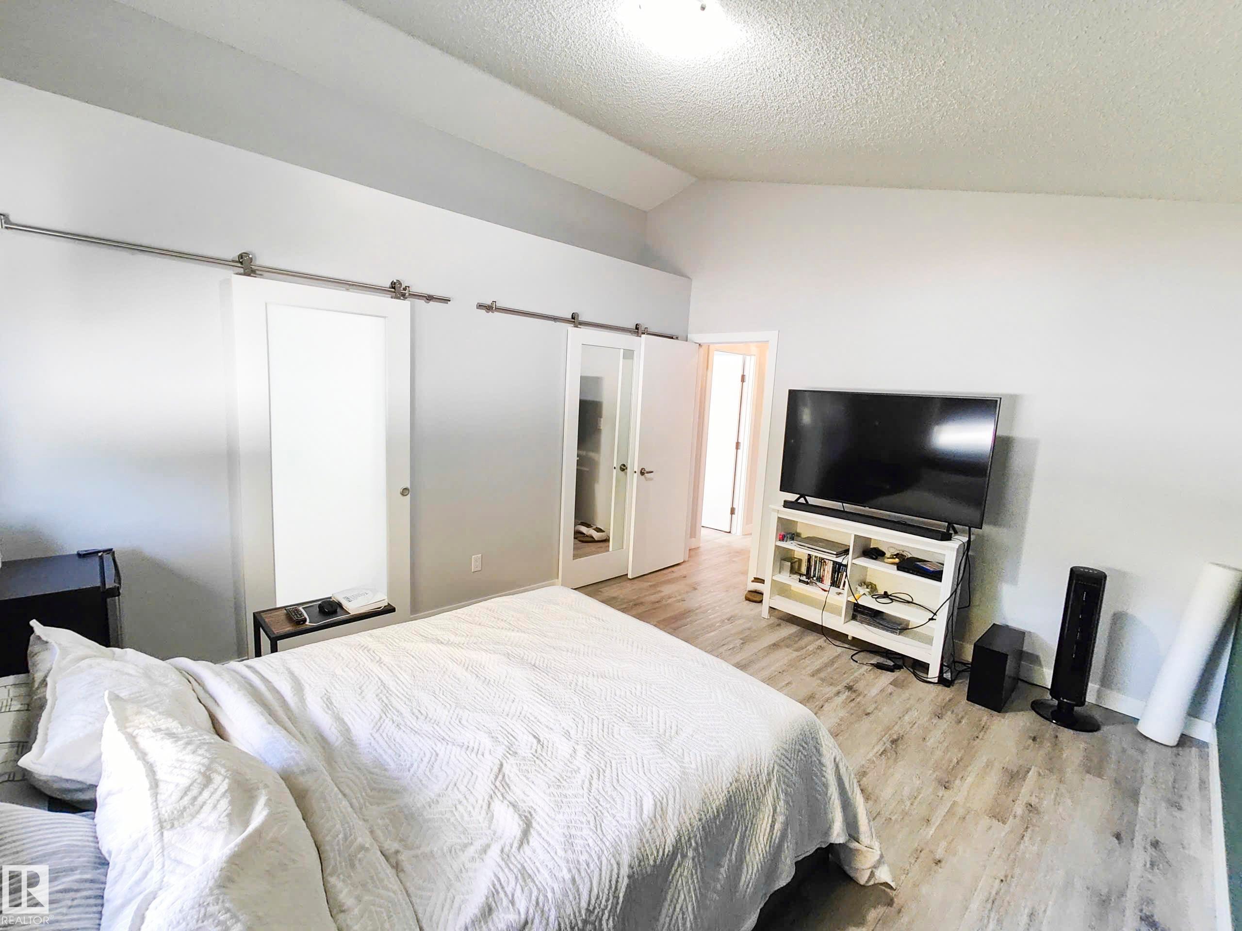 Vaulted ceiling, wood-finish flooring, white walls, and barn doors - 215 Peter Close Nw, Edmonton, AB