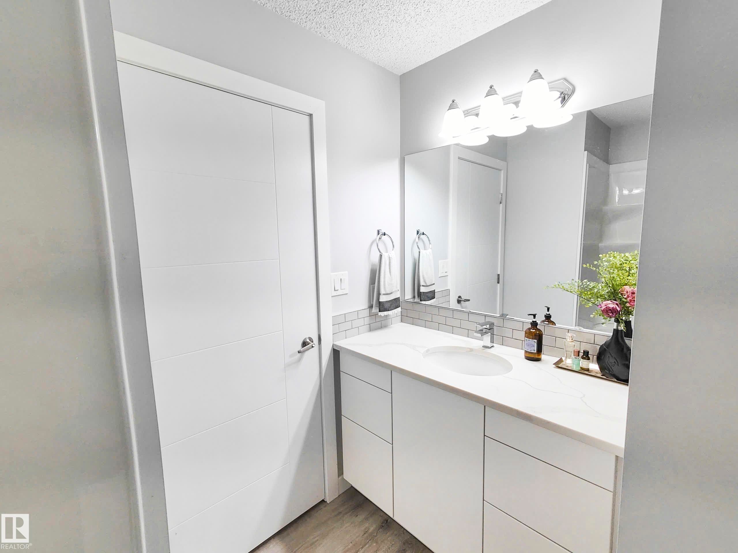 White vanity with integrated rectangular sink, stone-finish countertop, and white subway tile backsplash - 215 Peter Close Nw, Edmonton, AB