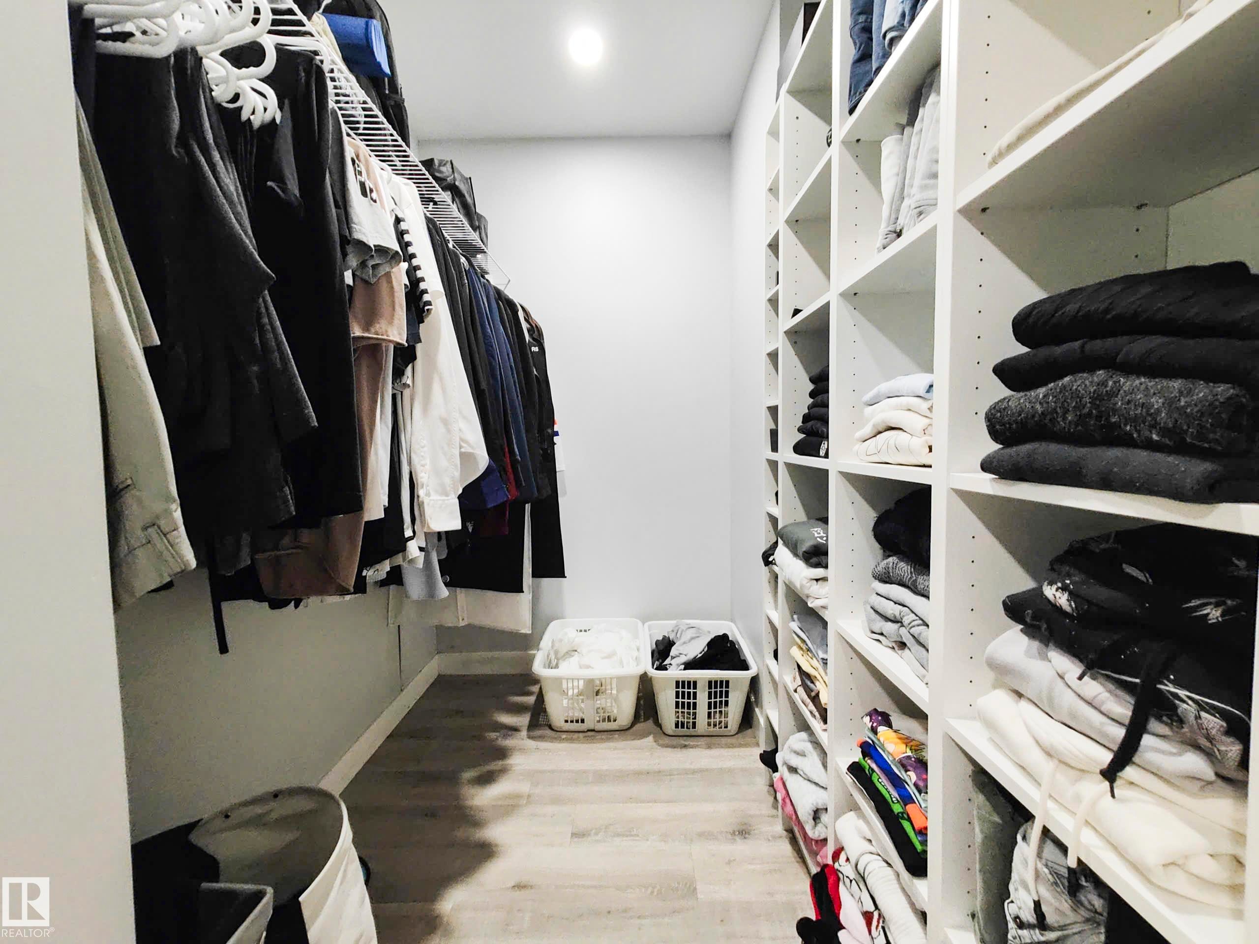 Walk-in closet featuring built-in shelving, hanging storage, wood-finish flooring, and recessed lighting - 215 Peter Close Nw, Edmonton, AB