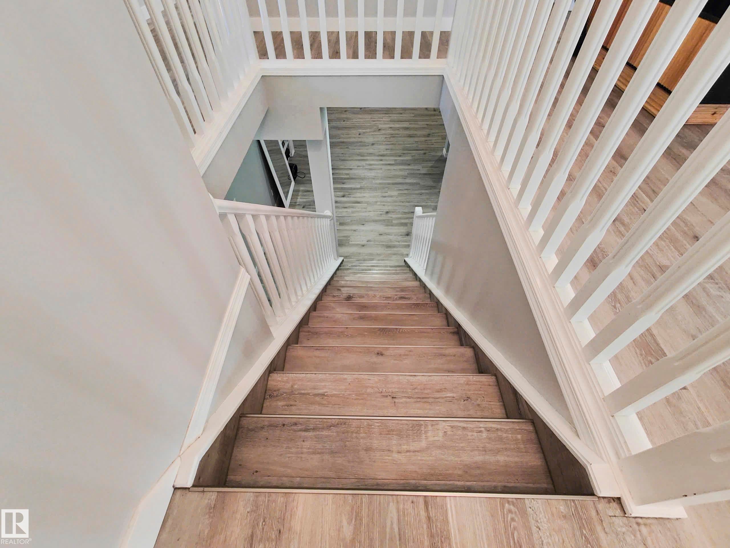 Staircase featuring wood-finish treads and risers with white balusters - 215 Peter Close Nw, Edmonton, AB