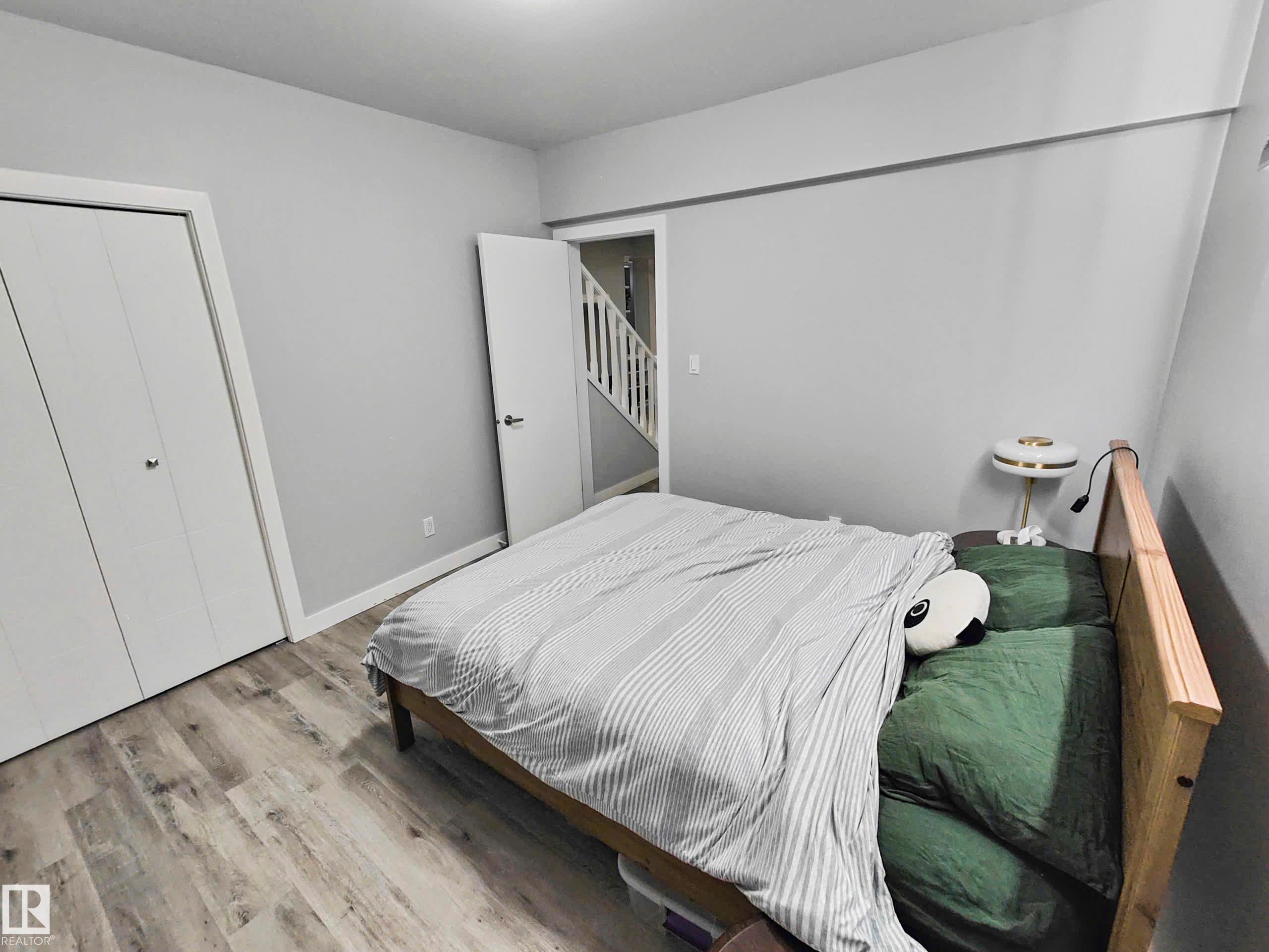 Neutral paint palette, wood-finish flooring, and white bifold closet doors - 215 Peter Close Nw, Edmonton, AB