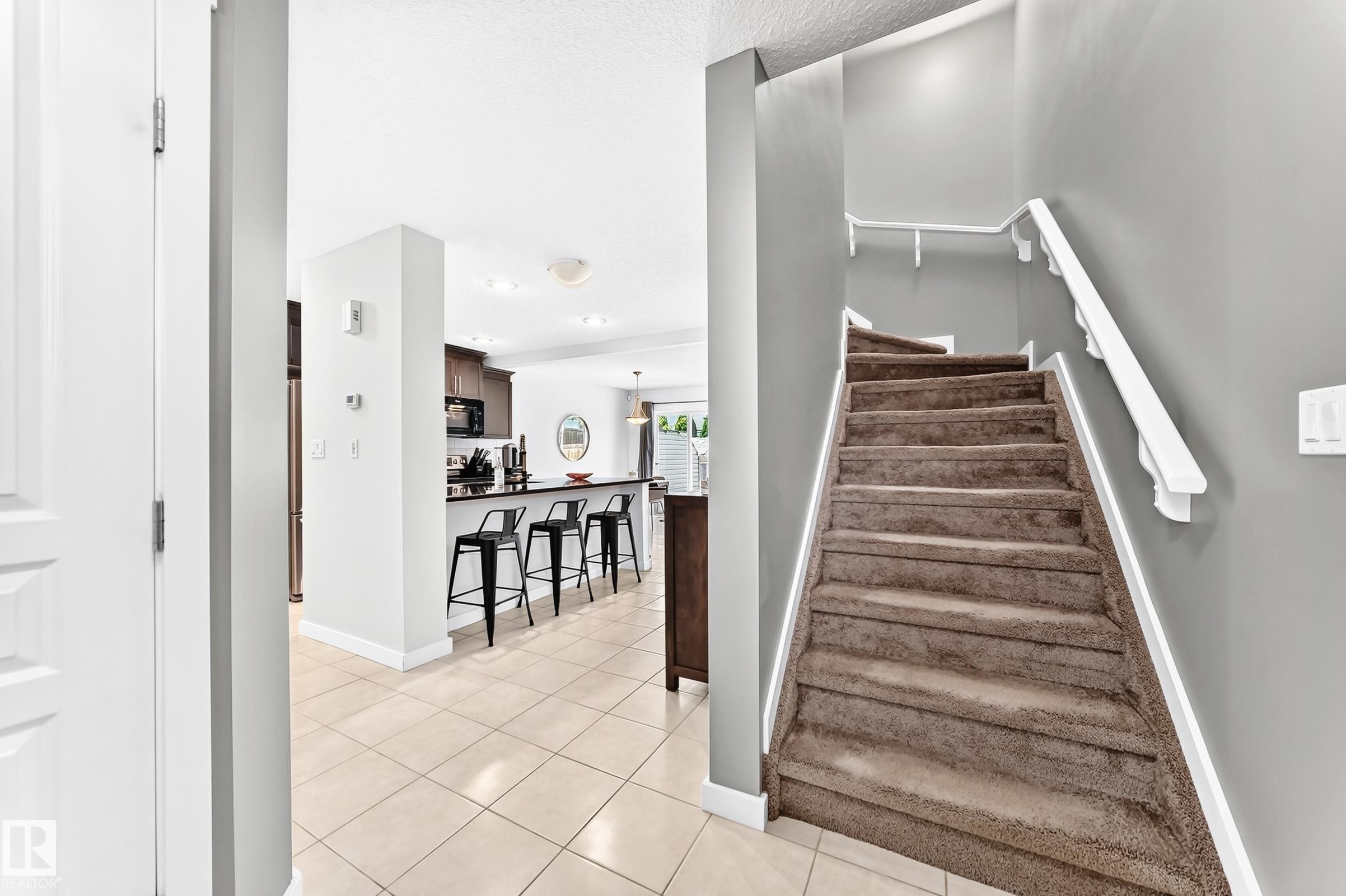Carpeted staircase with white handrails - 16832 53 Street Nw, Edmonton, AB