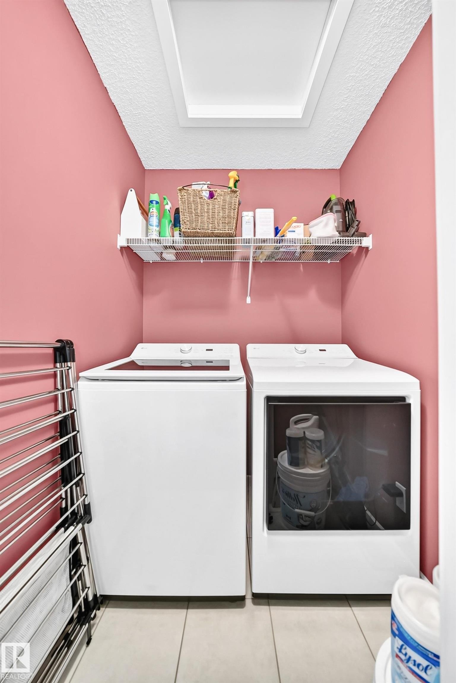 Laundry area featuring tile flooring, a built-in wire shelf, and a skylight - 16832 53 Street Nw, Edmonton, AB
