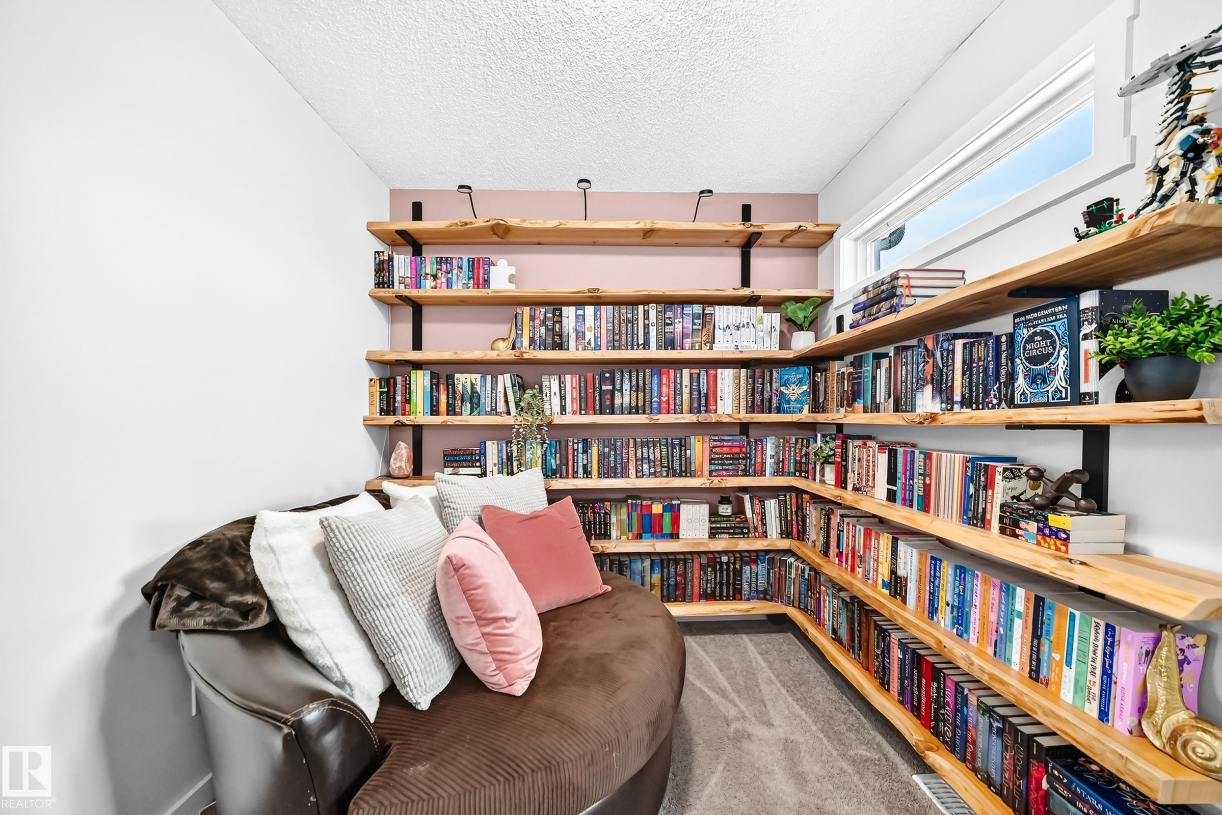 Built-in wood-finish shelving with black metal brackets, painted accent wall, and a long horizontal window - 16832 53 Street Nw, Edmonton, AB