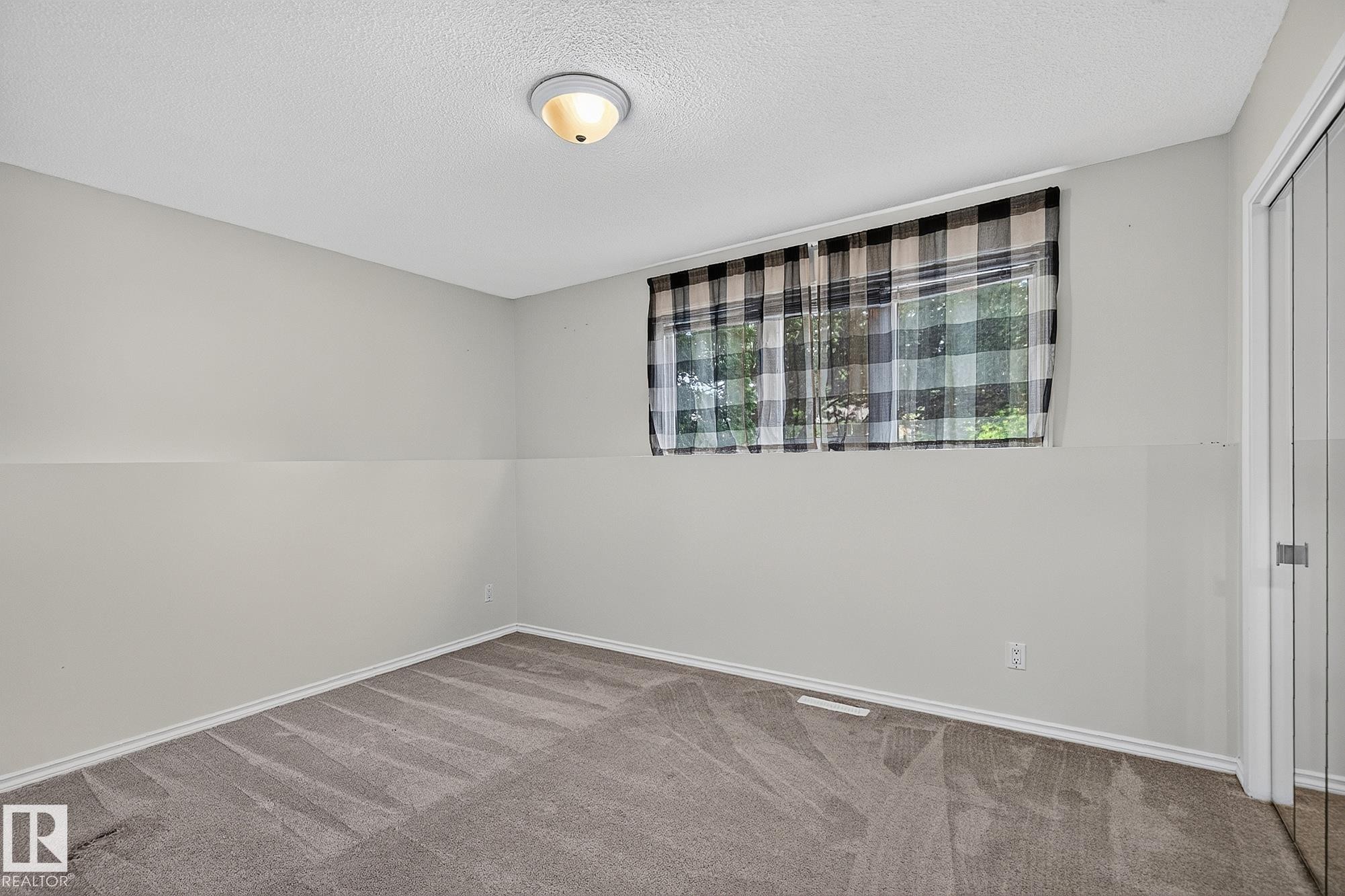 Recessed window with black and white plaid curtains, neutral painted walls, and gray carpet flooring - 16016 78A Avenue Nw, Edmonton, AB