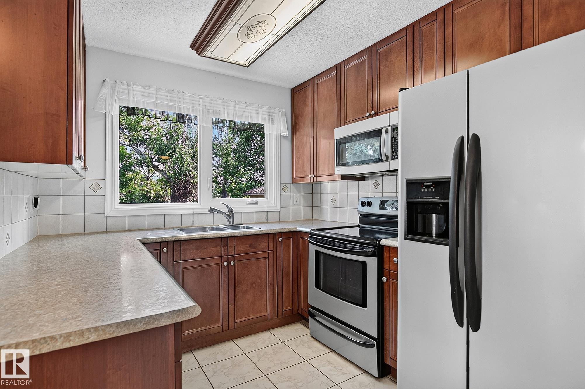 Wood-finish cabinetry paired with light-toned countertops - 16016 78A Avenue Nw, Edmonton, AB