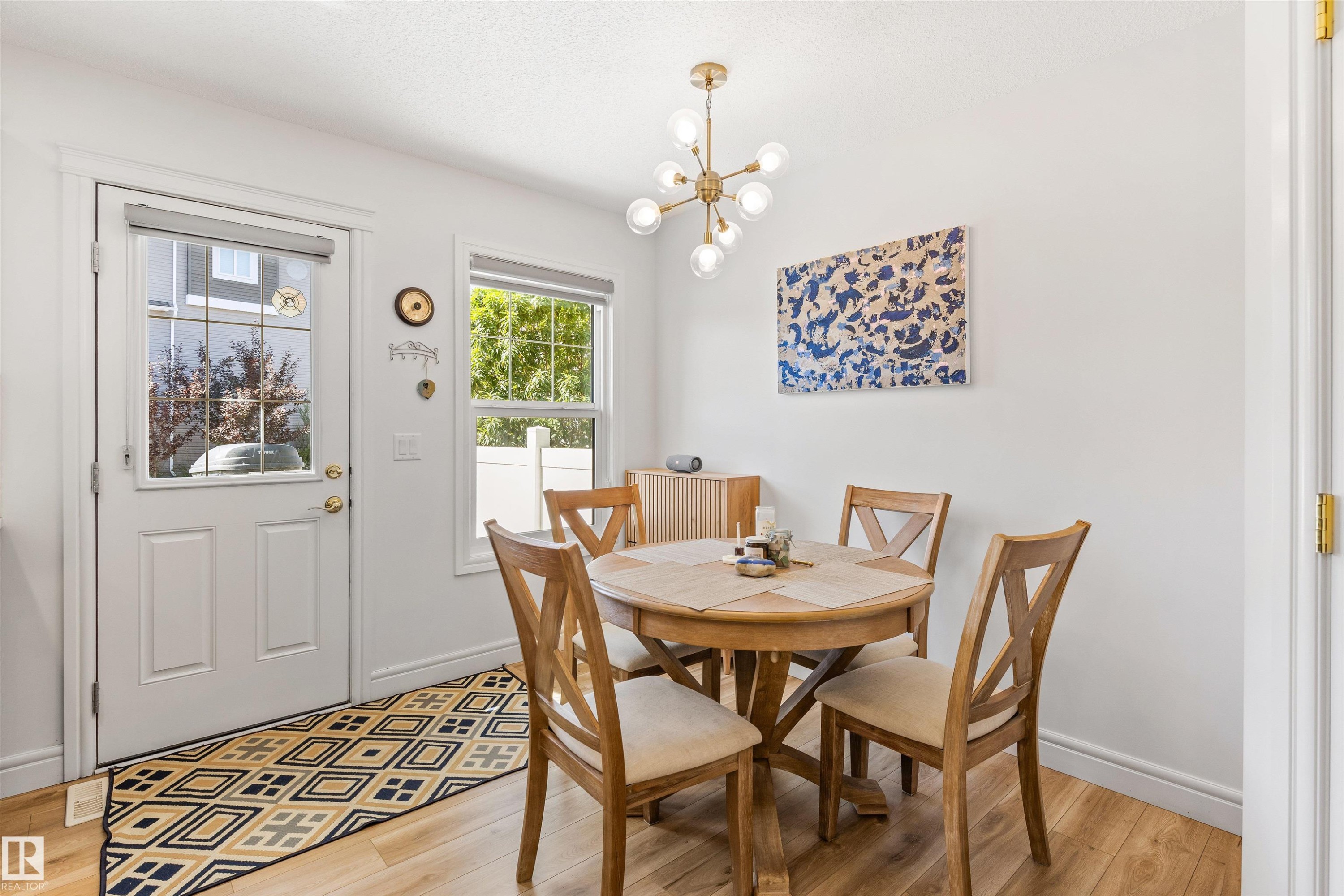 Wood-finish flooring, white walls, and a modern gold-finish chandelier with globe lighting - #71 330 Bulyea Rd Nw, Edmonton, AB