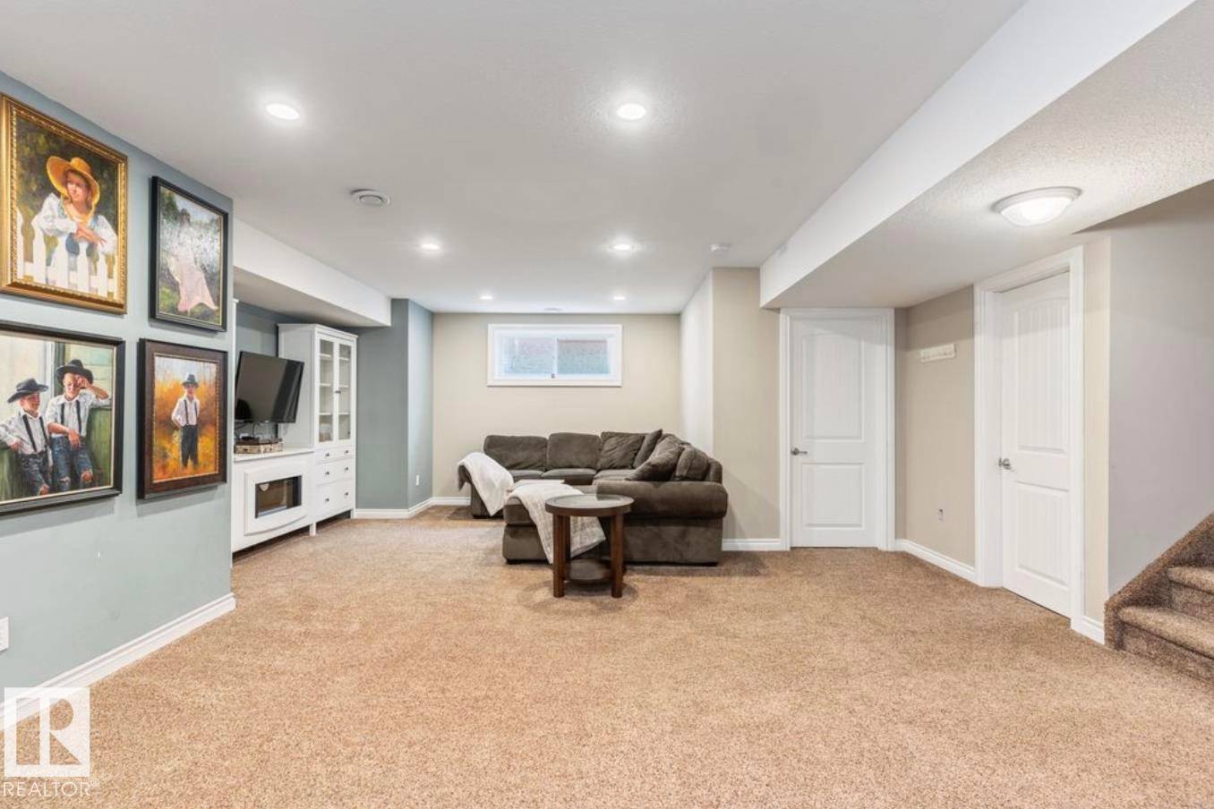 Recessed lighting illuminates the carpeted living area with a built-in media console and a window - 22 Voleta Crest, Spruce Grove, AB