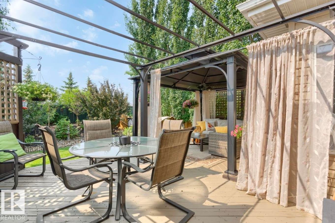 Expansive outdoor deck featuring a fixed pergola, additional covered gazebo, and mature landscaping - 22 Voleta Crest, Spruce Grove, AB