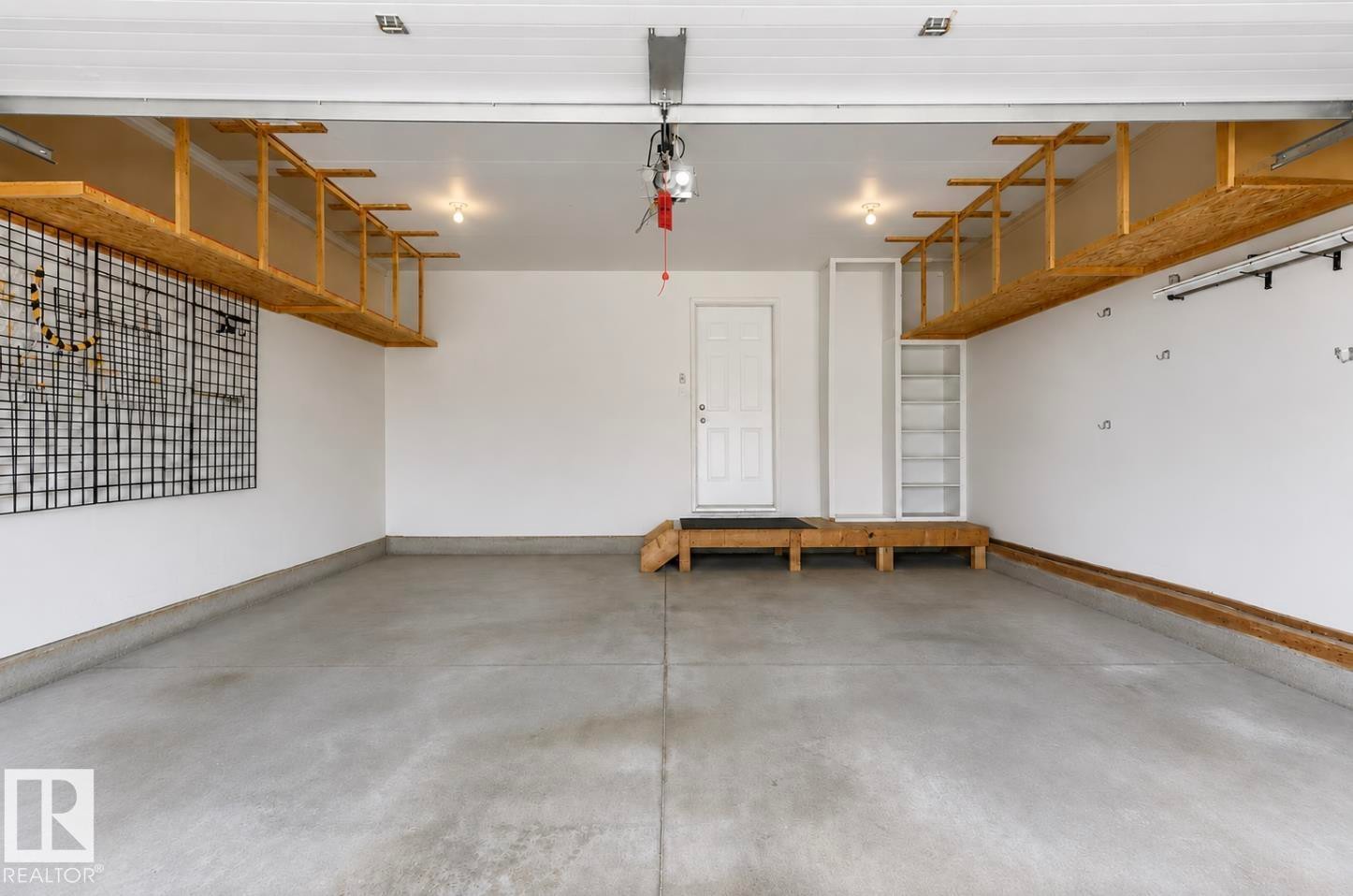 Concrete floor with finished baseboards, built-in overhead shelving, and white interior door - 22 Voleta Crest, Spruce Grove, AB