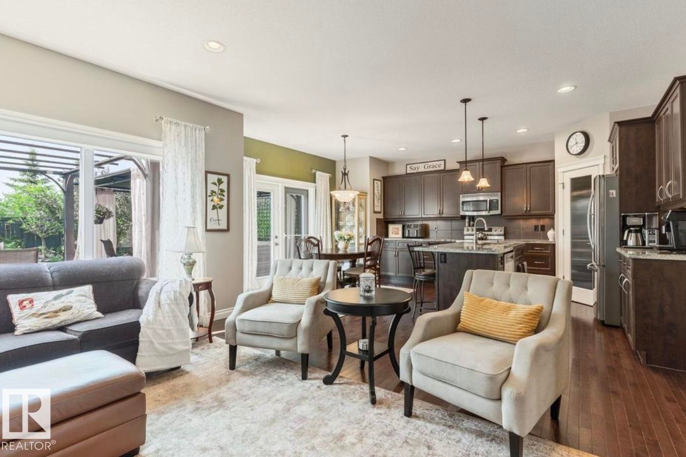 Open-concept living area with dark wood-finish flooring, recessed lighting, and a kitchen island with pendant lighting - 22 Voleta Crest, Spruce Grove, AB