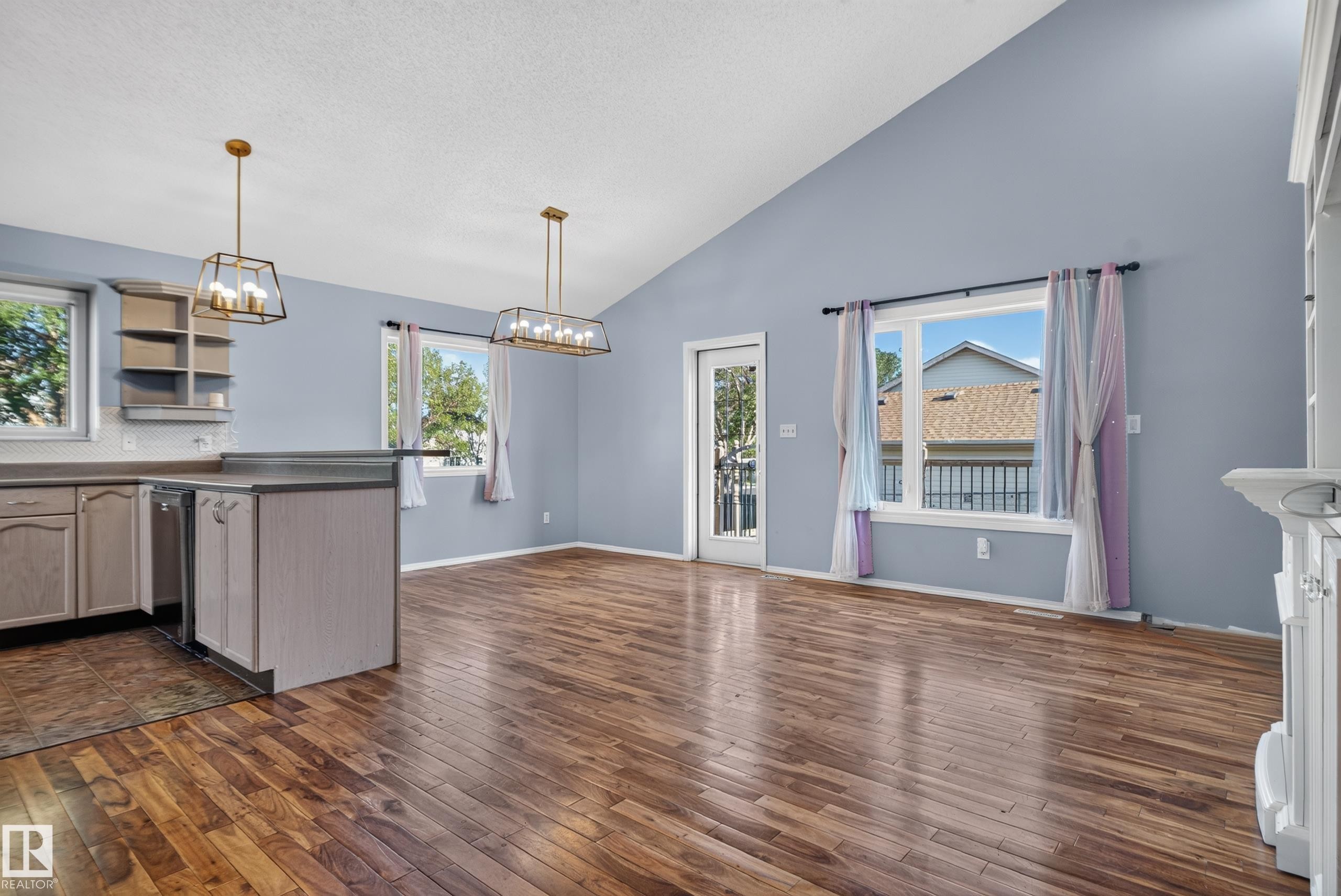Vaulted ceiling, wood-finish flooring, two large windows, a built-in kitchen island, and gold-finish light fixtures - 13803 130A Avenue Nw, Edmonton, AB