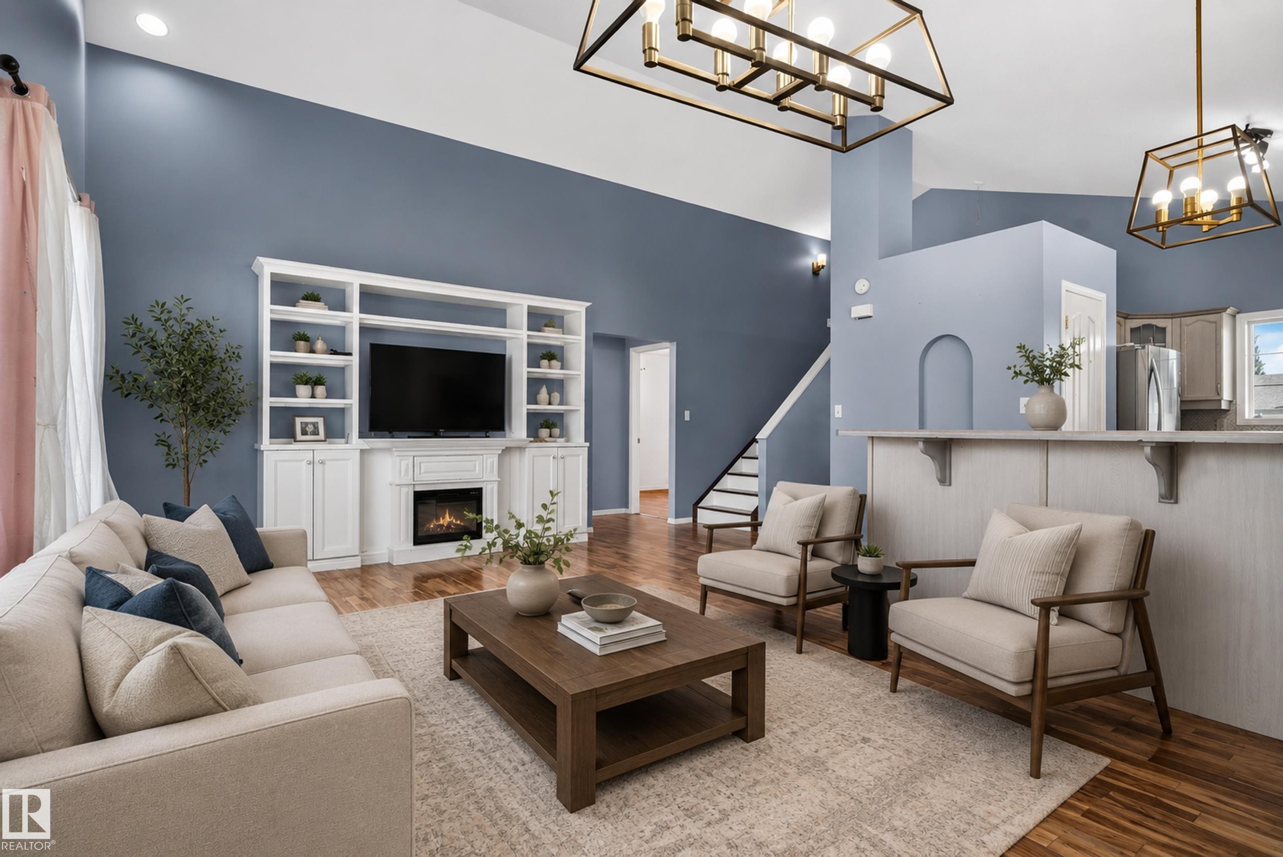 Vaulted ceilings, wood-finish flooring, built-in media center with fireplace, staircase with white risers, and decorative arched wall niche - 13803 130A Avenue Nw, Edmonton, AB
