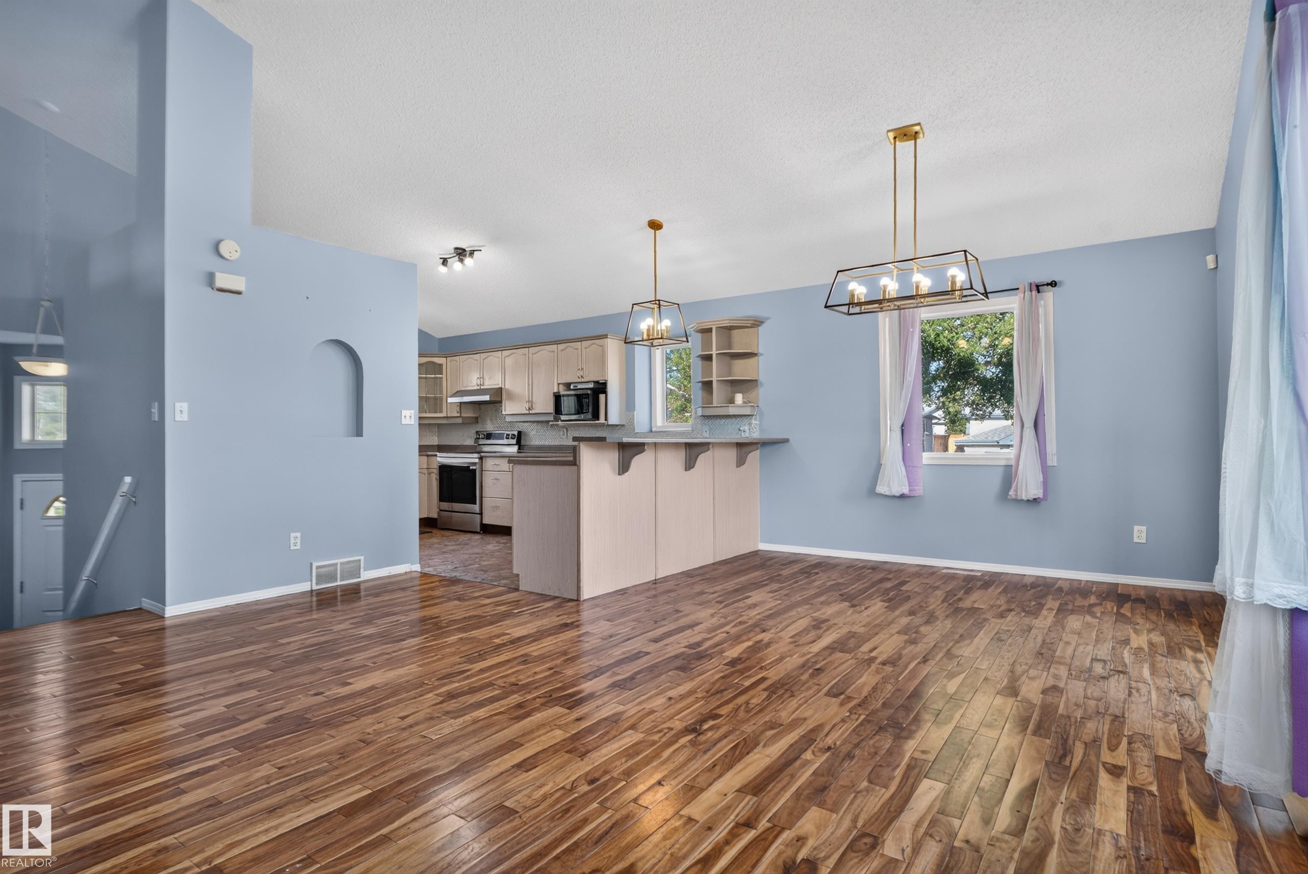 Wood-finish flooring throughout, with a kitchen featuring light cabinetry and stainless steel appliances - 13803 130A Avenue Nw, Edmonton, AB