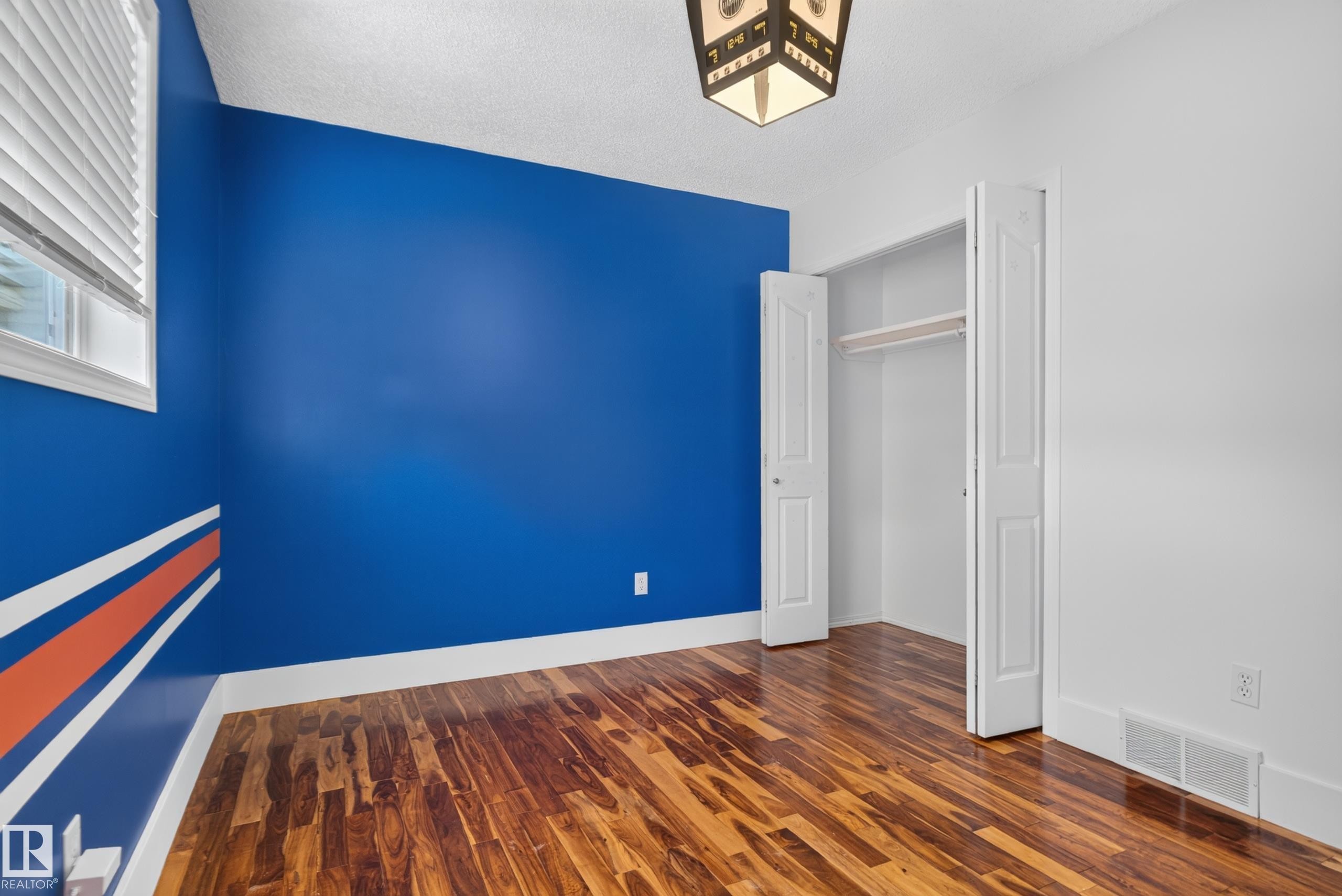Hardwood flooring, painted accent wall, window with blinds, and a built-in closet with bi-fold doors - 13803 130A Avenue Nw, Edmonton, AB