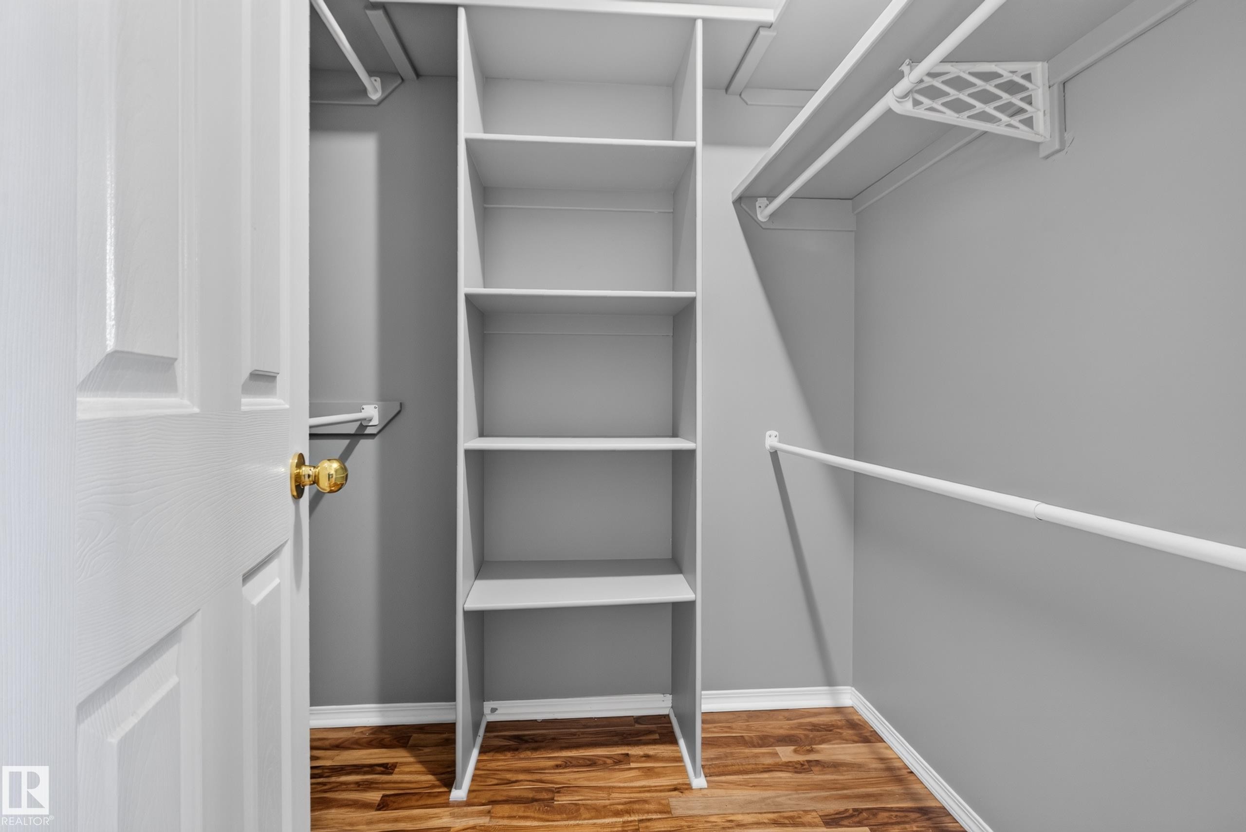 Built-in shelving unit providing storage, multiple clothing rods, and wood-finish flooring - 13803 130A Avenue Nw, Edmonton, AB