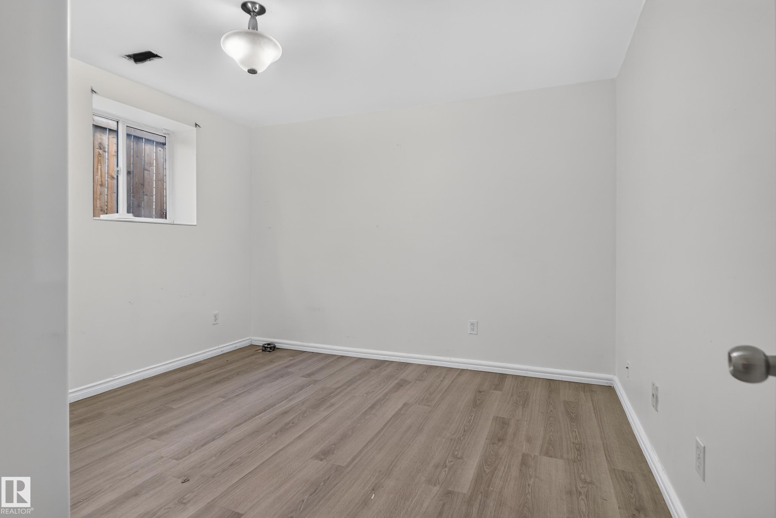 Wood-finish flooring with white baseboards, recessed window, and flush mount lighting - 13803 130A Avenue Nw, Edmonton, AB