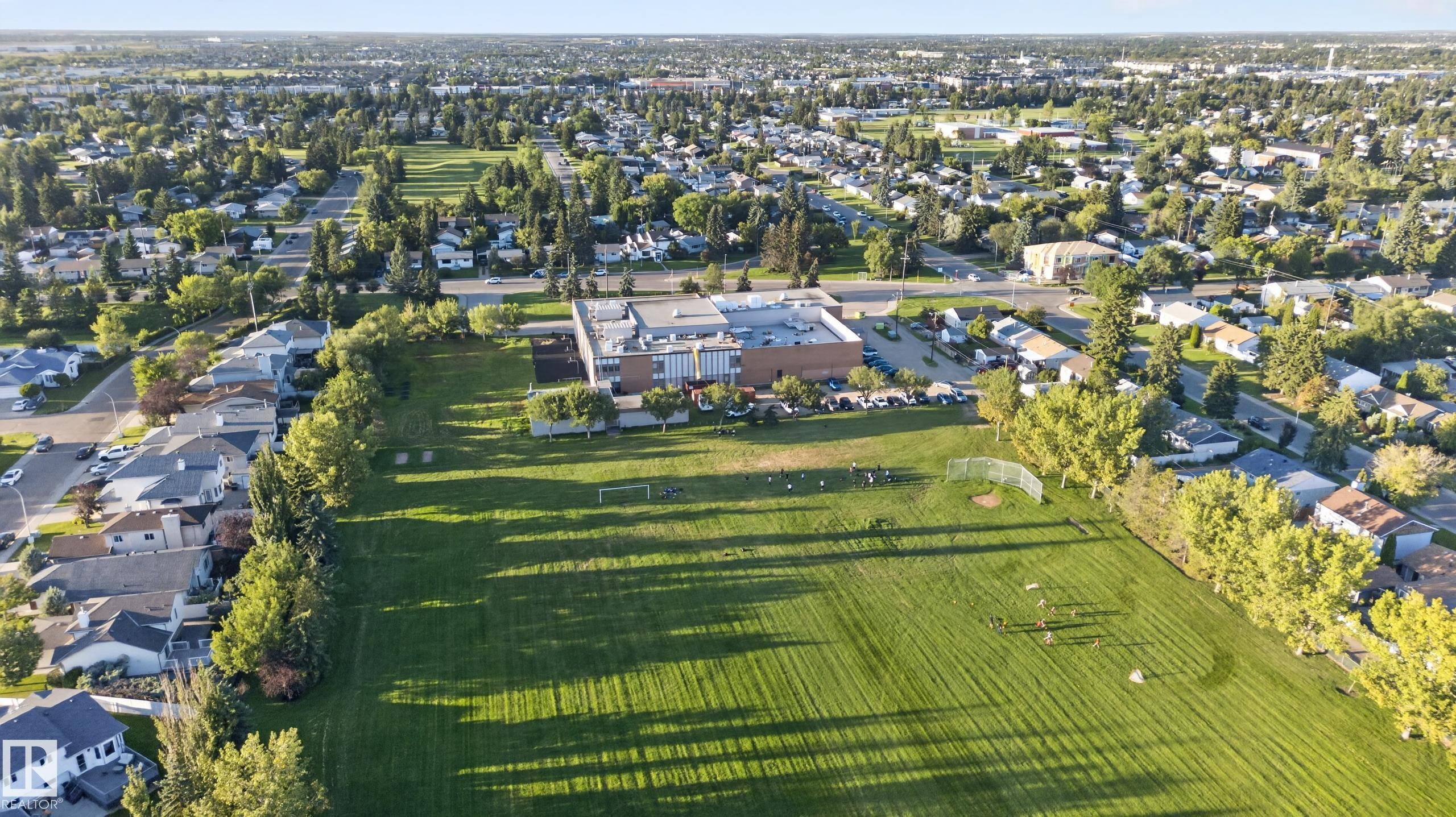 Expansive green space featuring a large field, adjacent community building, and surrounding residential areas - 13803 130A Avenue Nw, Edmonton, AB