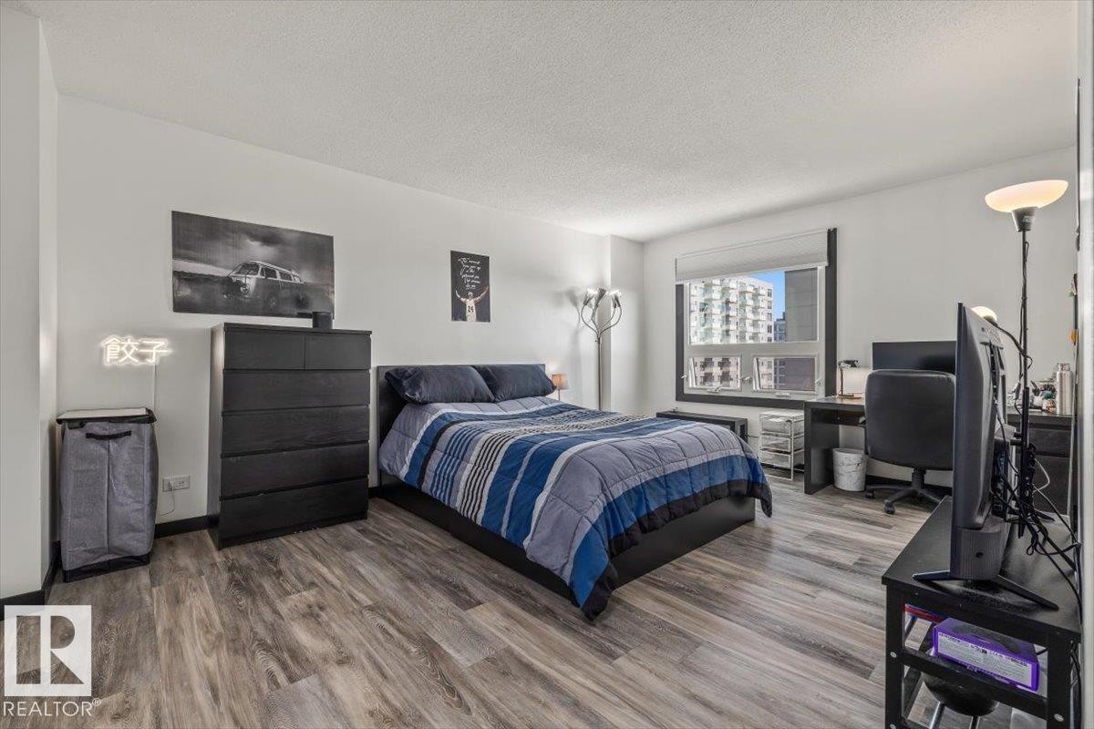 Wood-finish flooring throughout, white wall paint, and a window with roller shade - #906 12303 Jasper Av Nw, Edmonton, AB