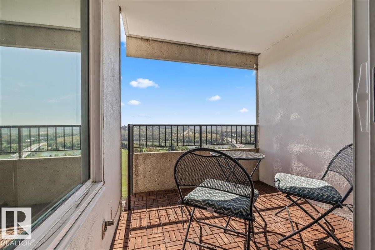 Outdoor balcony with wood-finish tile flooring, concrete walls, and a black metal railing - #906 12303 Jasper Av Nw, Edmonton, AB