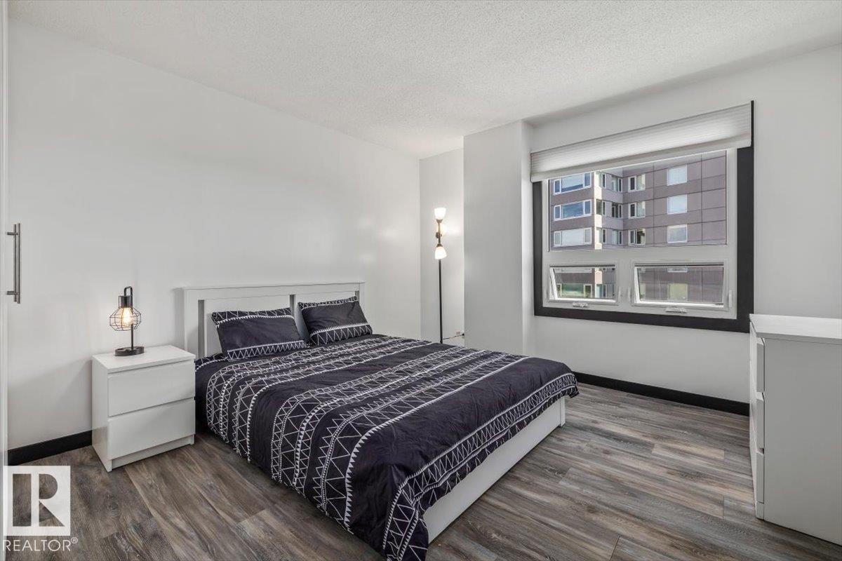 Wood-finish flooring, white walls, and a large window with roller shades - #906 12303 Jasper Av Nw, Edmonton, AB