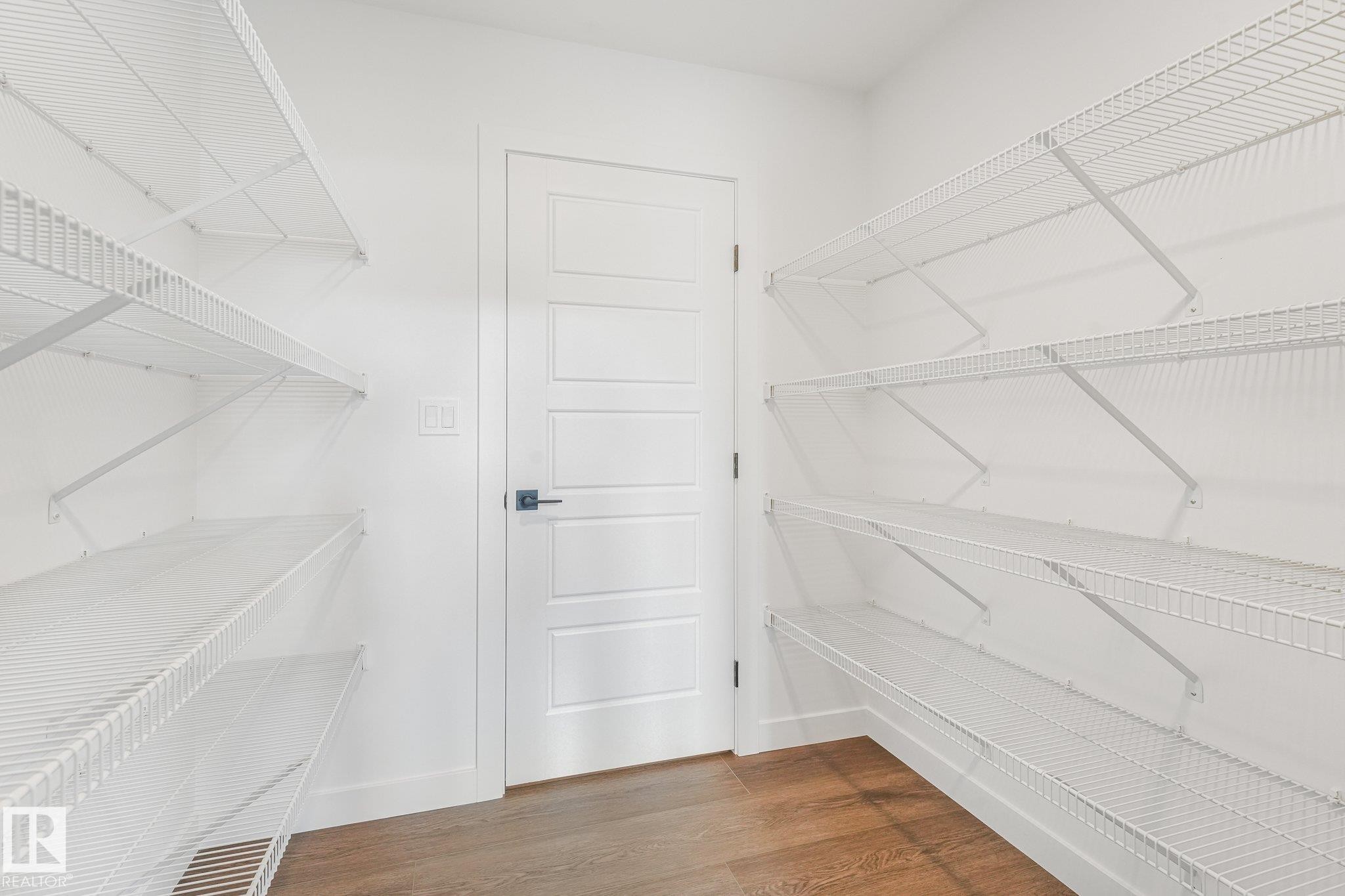 White wire shelving system, contemporary paneled door, dark hardware, wood-finish flooring, and crisp white walls - 511 157 Avenue Ne, Edmonton, AB