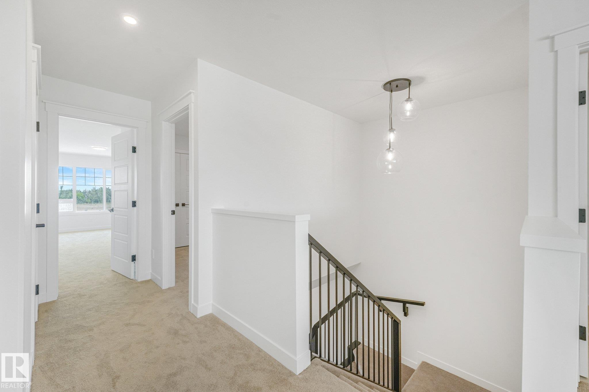 Recessed lighting and a decorative pendant light fixture illuminate the hallway and staircase - 511 157 Avenue Ne, Edmonton, AB