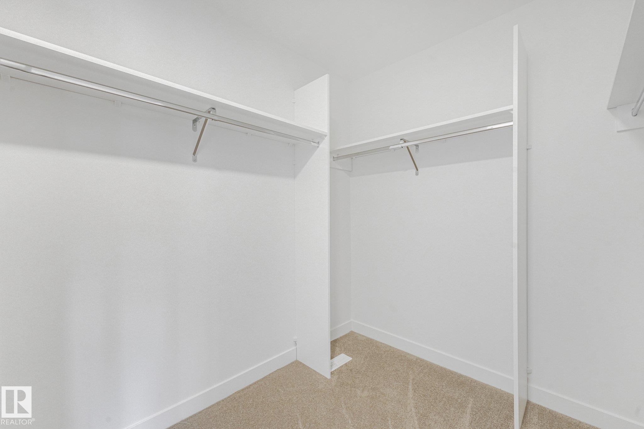 Built-in closet shelving with hanging rods and neutral carpet flooring - 511 157 Avenue Ne, Edmonton, AB