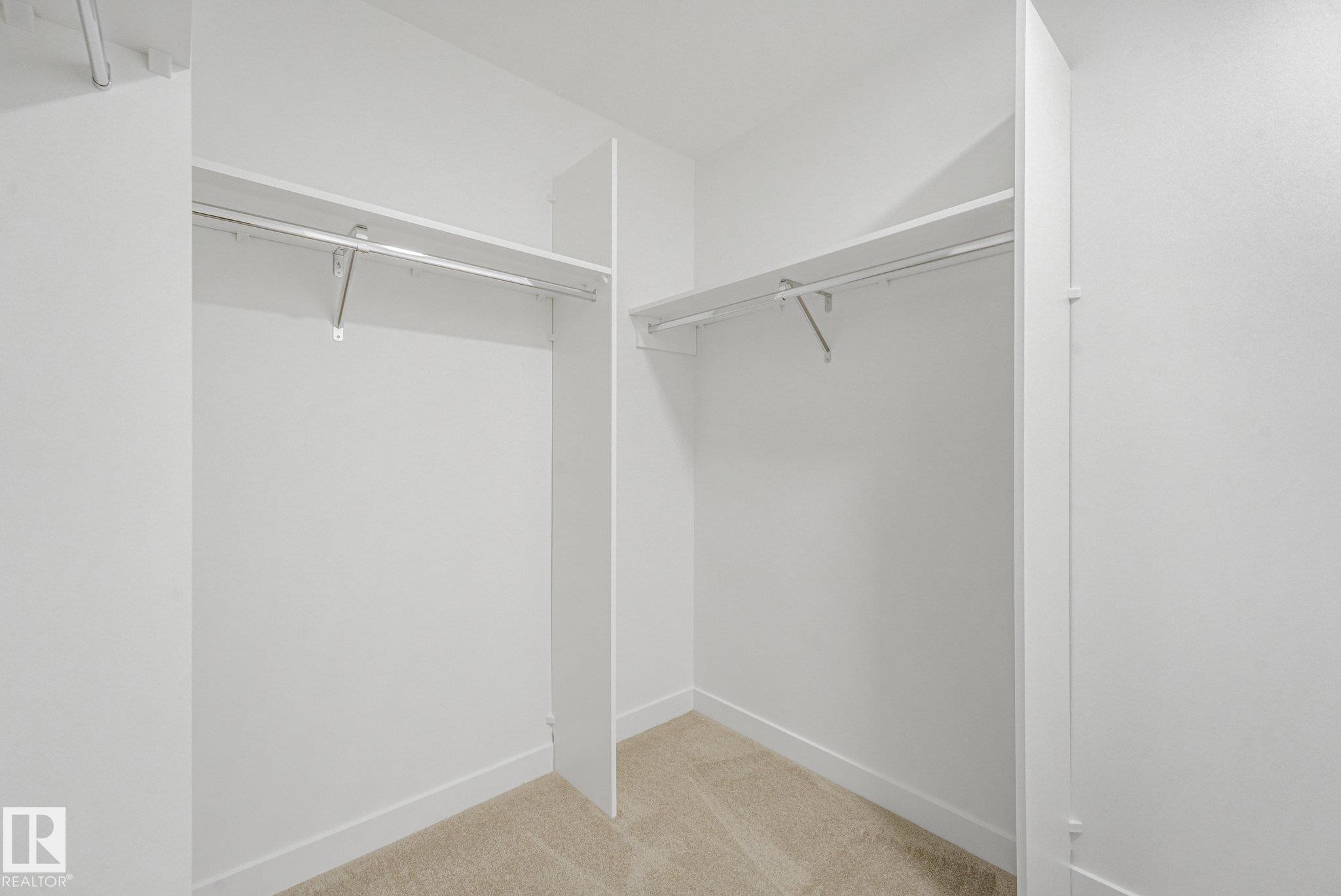 Spacious walk-in closet featuring dual clothing rods, generous shelving, and wood-finish flooring throughout - 511 157 Avenue Ne, Edmonton, AB