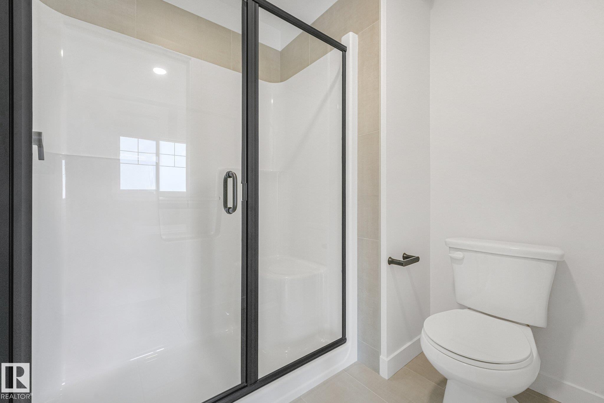 Glass-enclosed shower with a matte black frame, white shower base, and light-toned wall tile - 511 157 Avenue Ne, Edmonton, AB