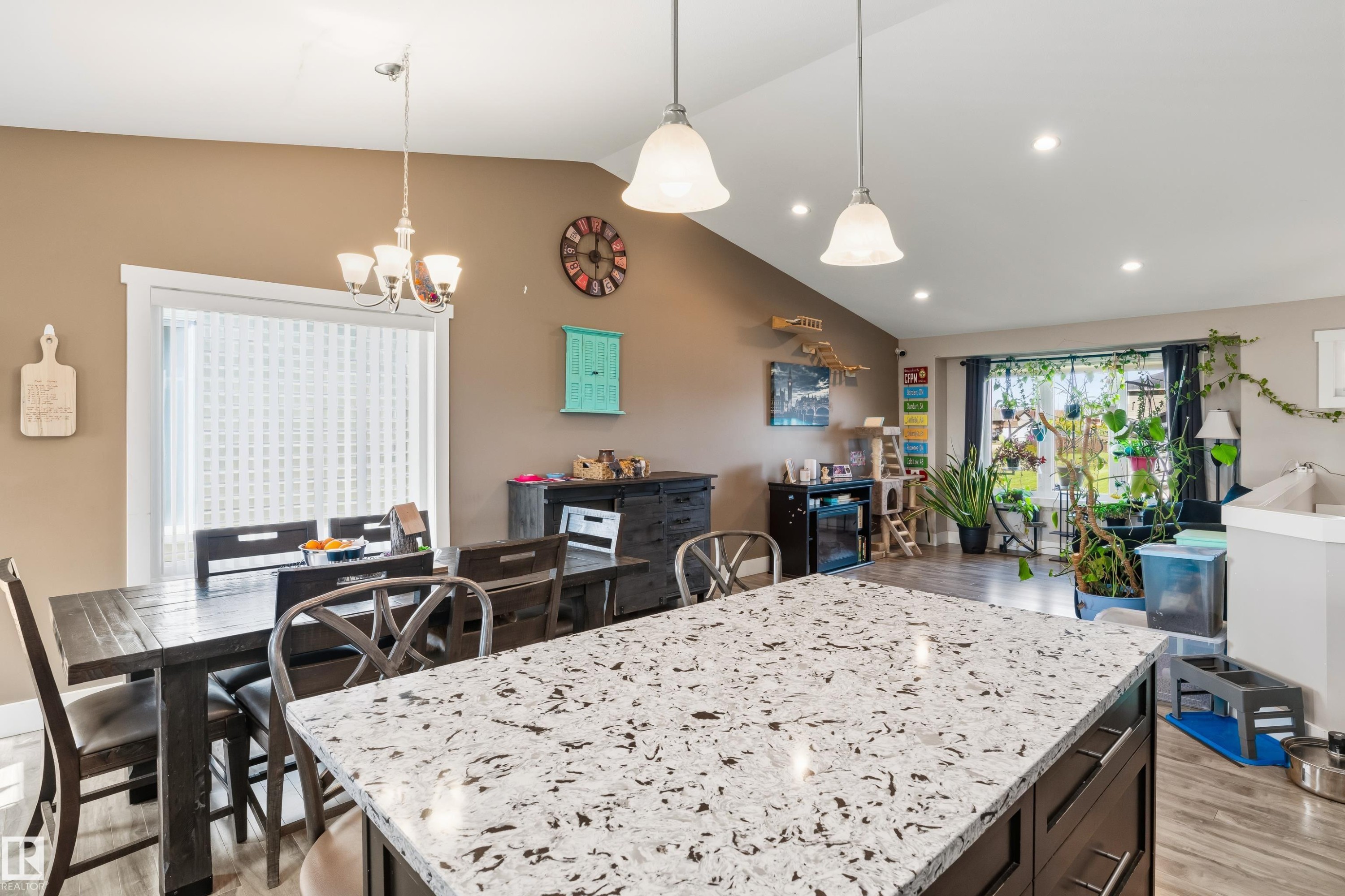 Kitchen island with a speckled countertop, dark wood-finish cabinetry, and pendant lighting - 4927 57 Avenue, Cold Lake, AB