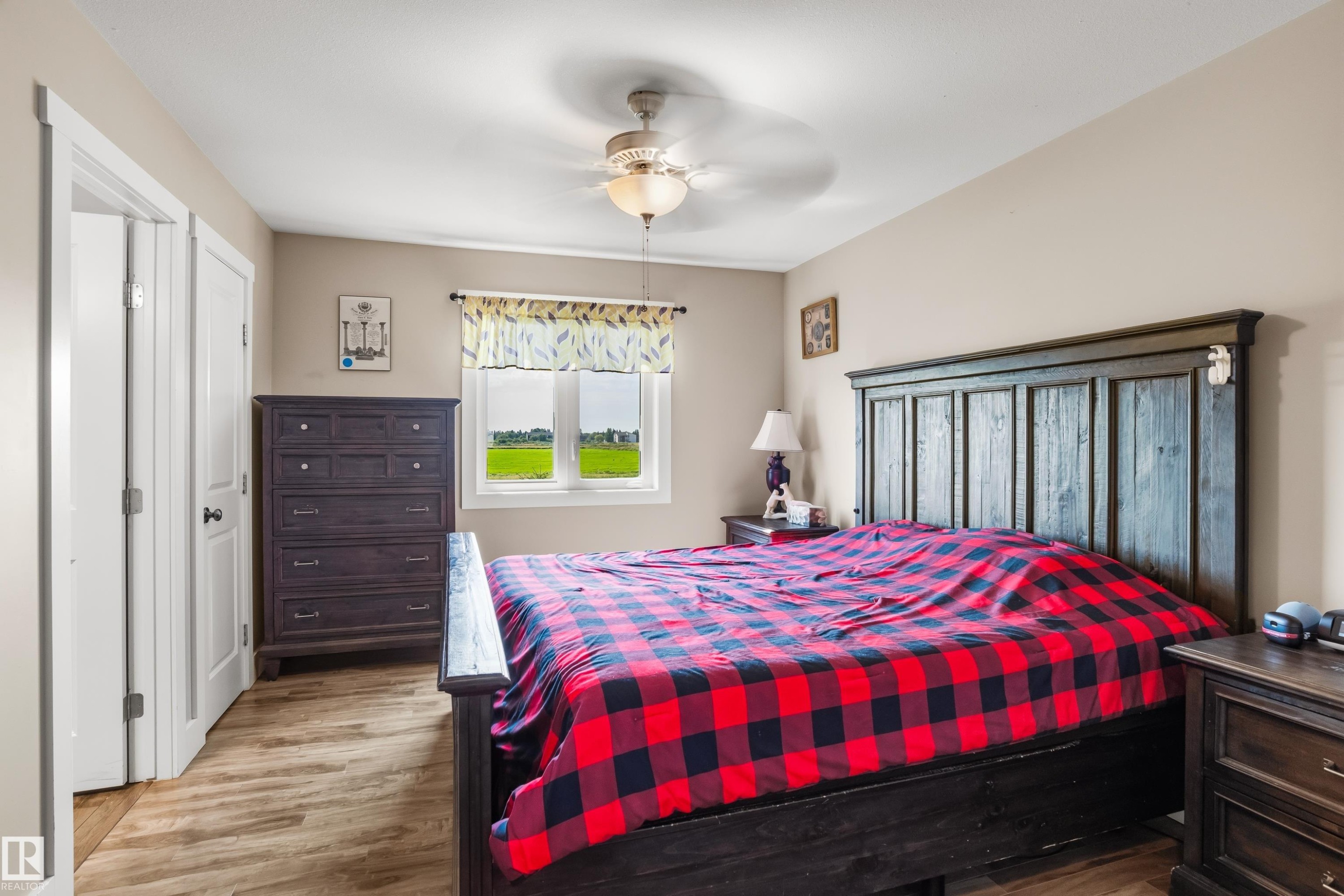 Wood-finish flooring, ceiling fan with integrated lighting, window with exterior scenery, paneled interior doors, and neutral wall tones - 4927 57 Avenue, Cold Lake, AB