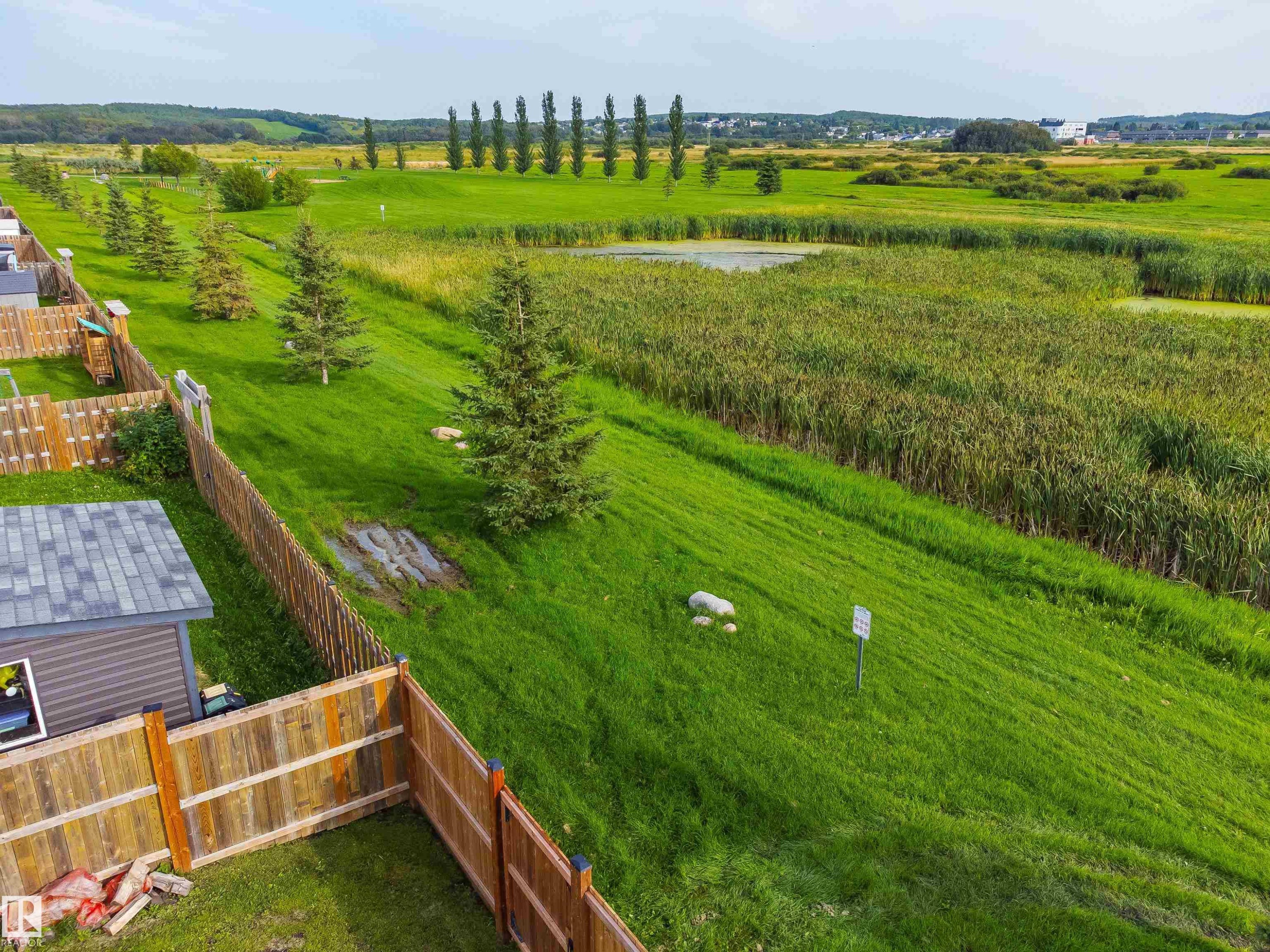 Expansive green space featuring a natural water body and mature greenery - 4927 57 Avenue, Cold Lake, AB
