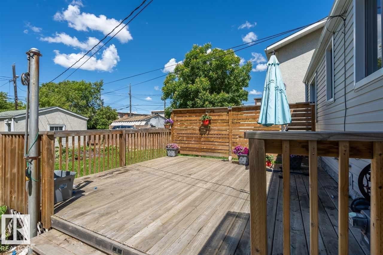 Wood-deck outdoor living space featuring a wood privacy fence and wood railing - 11730 125 Street Nw, Edmonton, AB