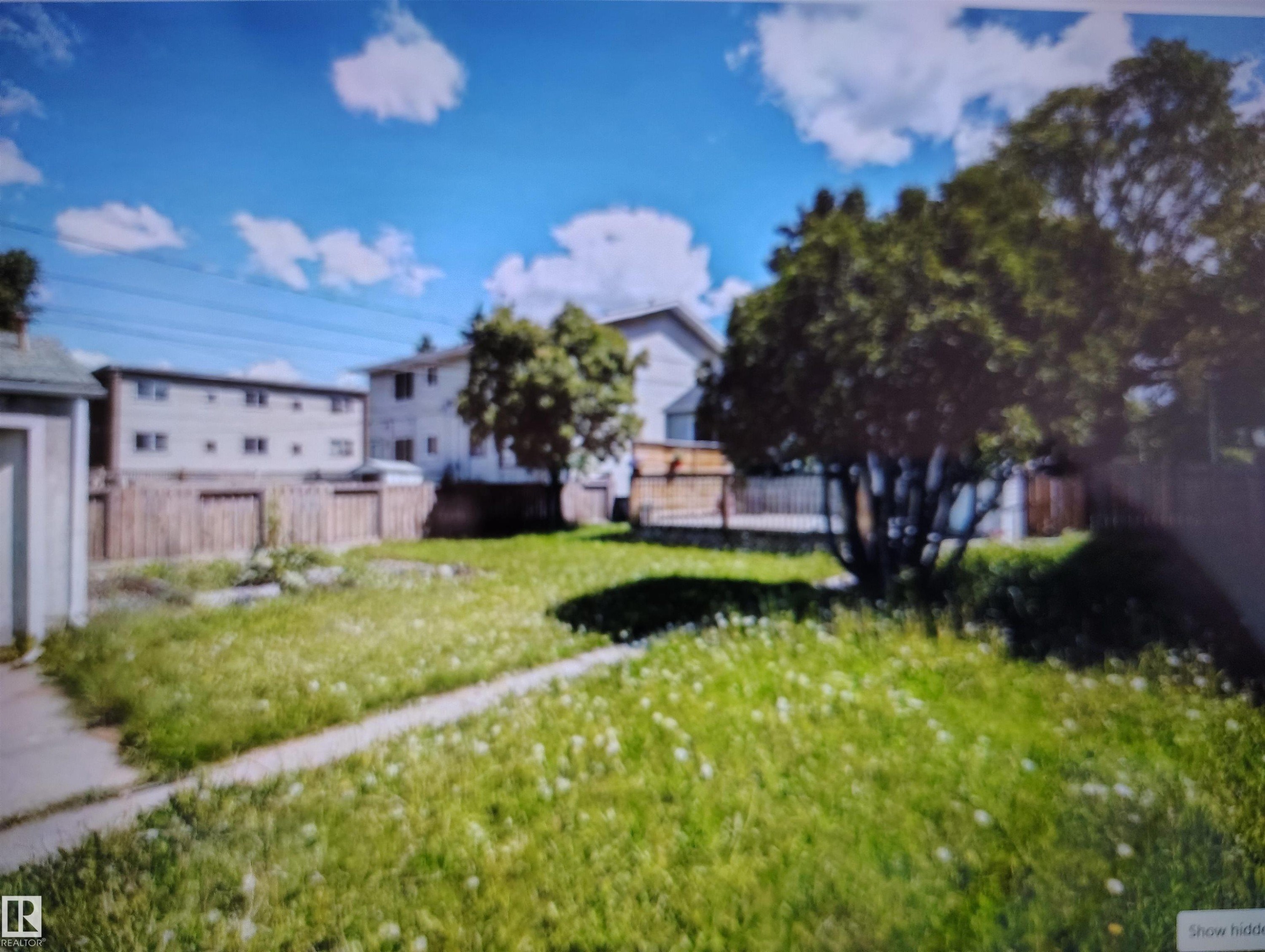 Expansive yard featuring a large grassy area, mature trees, and wood fencing - 11730 125 Street Nw, Edmonton, AB