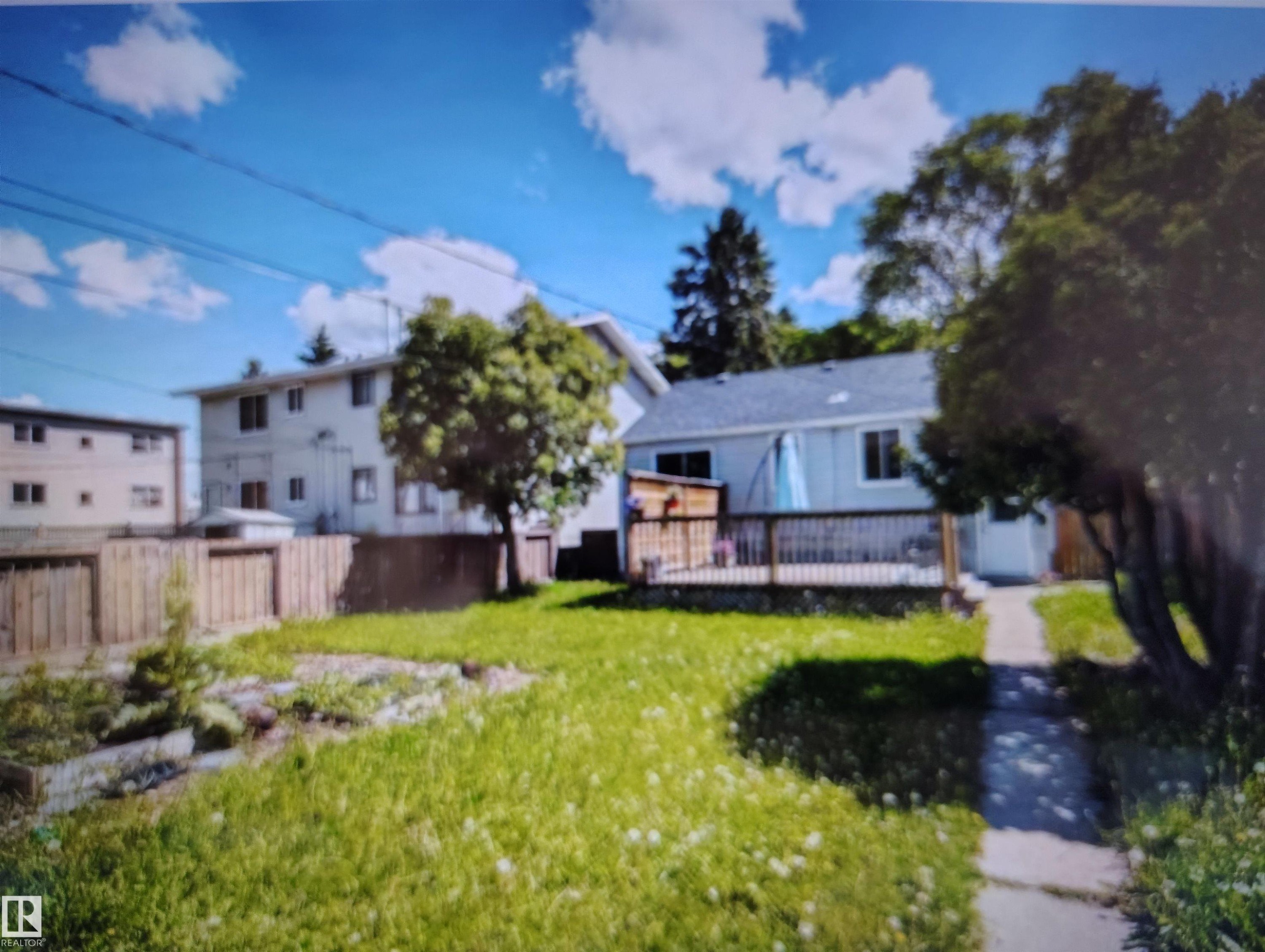 Expansive backyard featuring a wood deck, mature trees, and a concrete pathway - 11730 125 Street Nw, Edmonton, AB