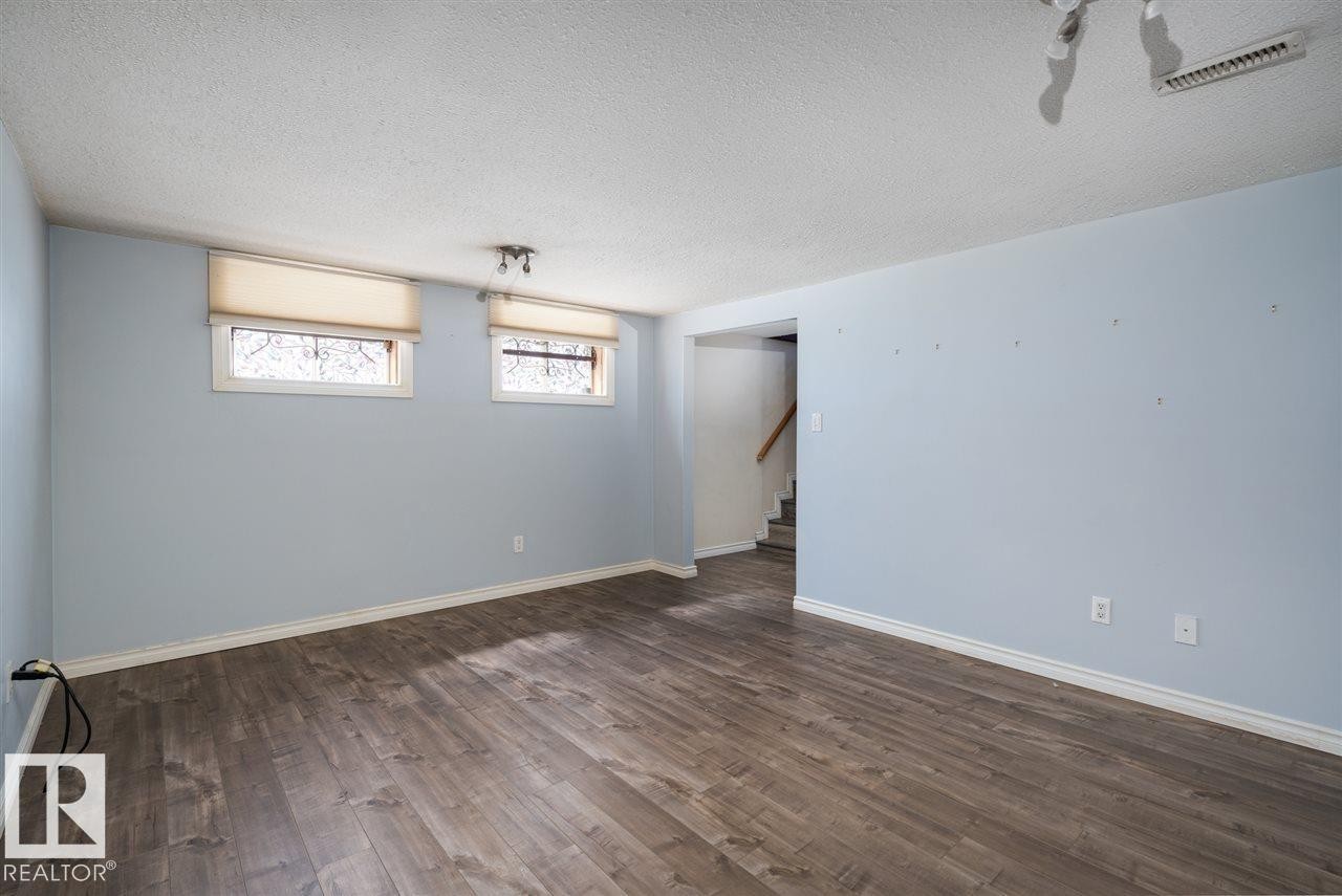 Wood-finish flooring, light blue walls, two windows with roller shades, and track lighting - 11730 125 Street Nw, Edmonton, AB
