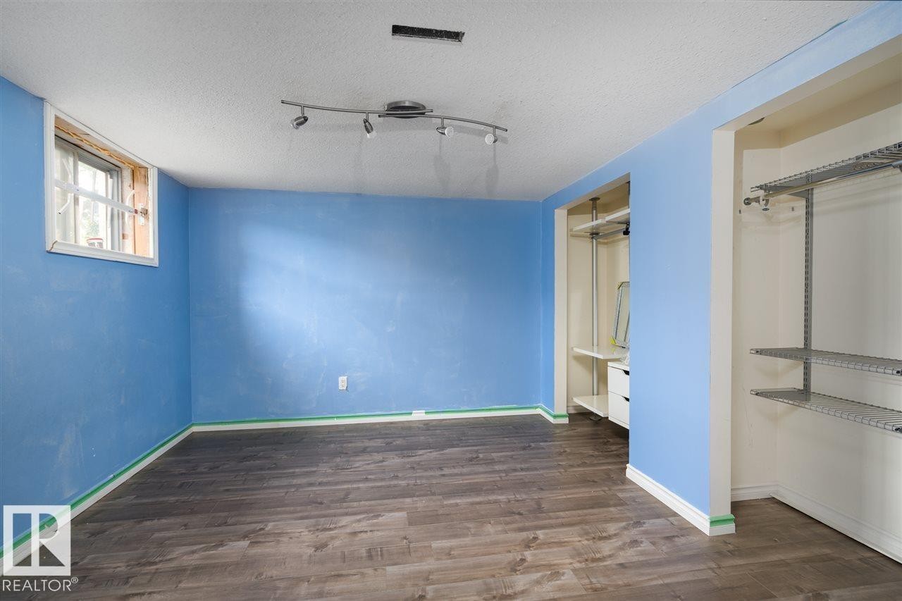 Spacious room featuring wood-finish flooring, a window, track lighting, and two built-in closet systems - 11730 125 Street Nw, Edmonton, AB