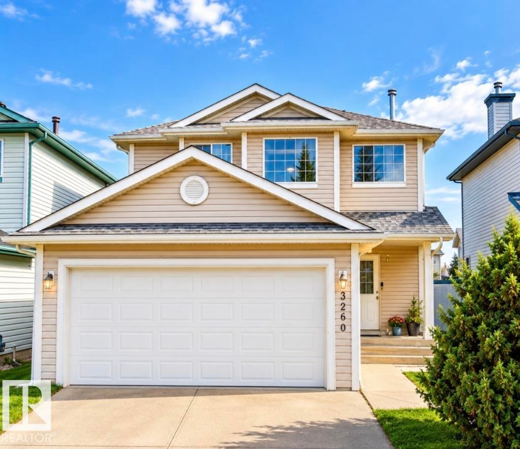Two-story residence with neutral-toned siding, attached double-door garage, and a concrete driveway - 3236 27 Avenue Nw, Edmonton, AB
