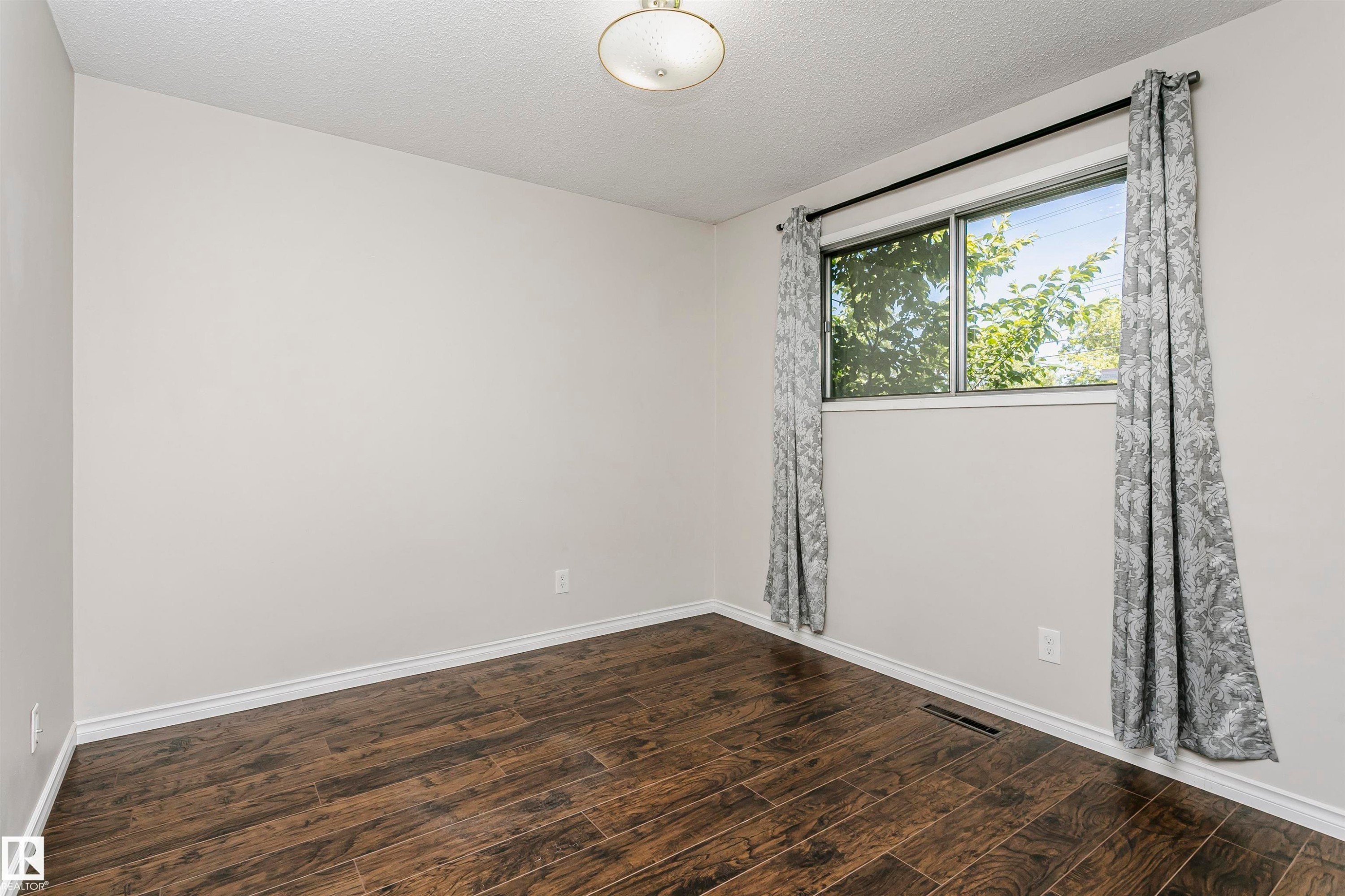 Wood-finish flooring, white trim, and a flush mount light fixture - 11440 44A Avenue Nw, Edmonton, AB