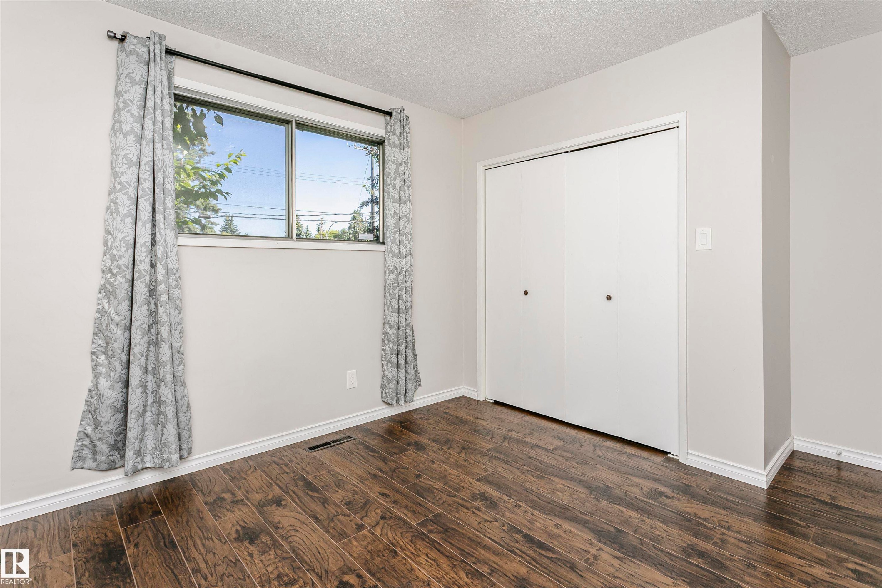 Wood-finish flooring, white walls, and a sliding door closet - 11440 44A Avenue Nw, Edmonton, AB