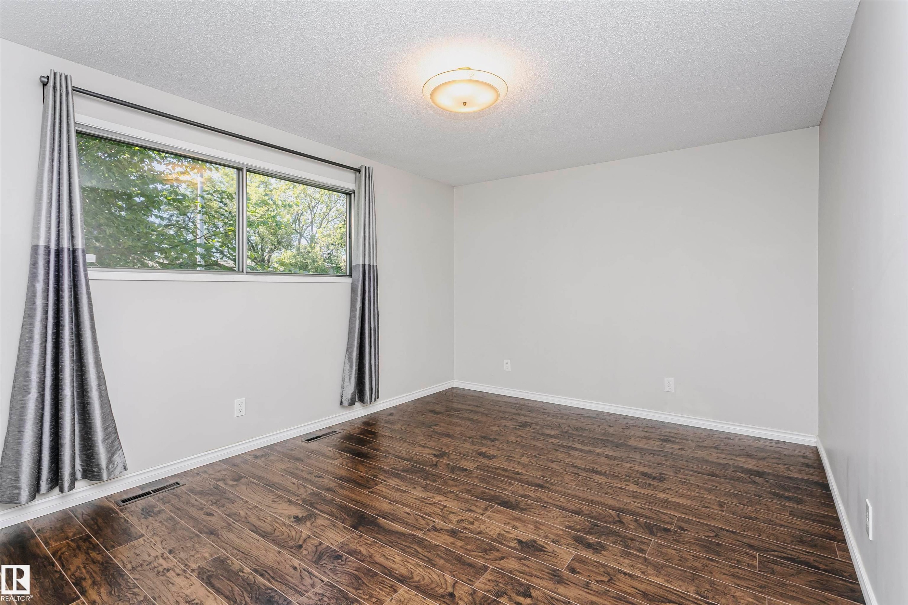 Wood-finish flooring, white walls, and a window with a silver frame - 11440 44A Avenue Nw, Edmonton, AB