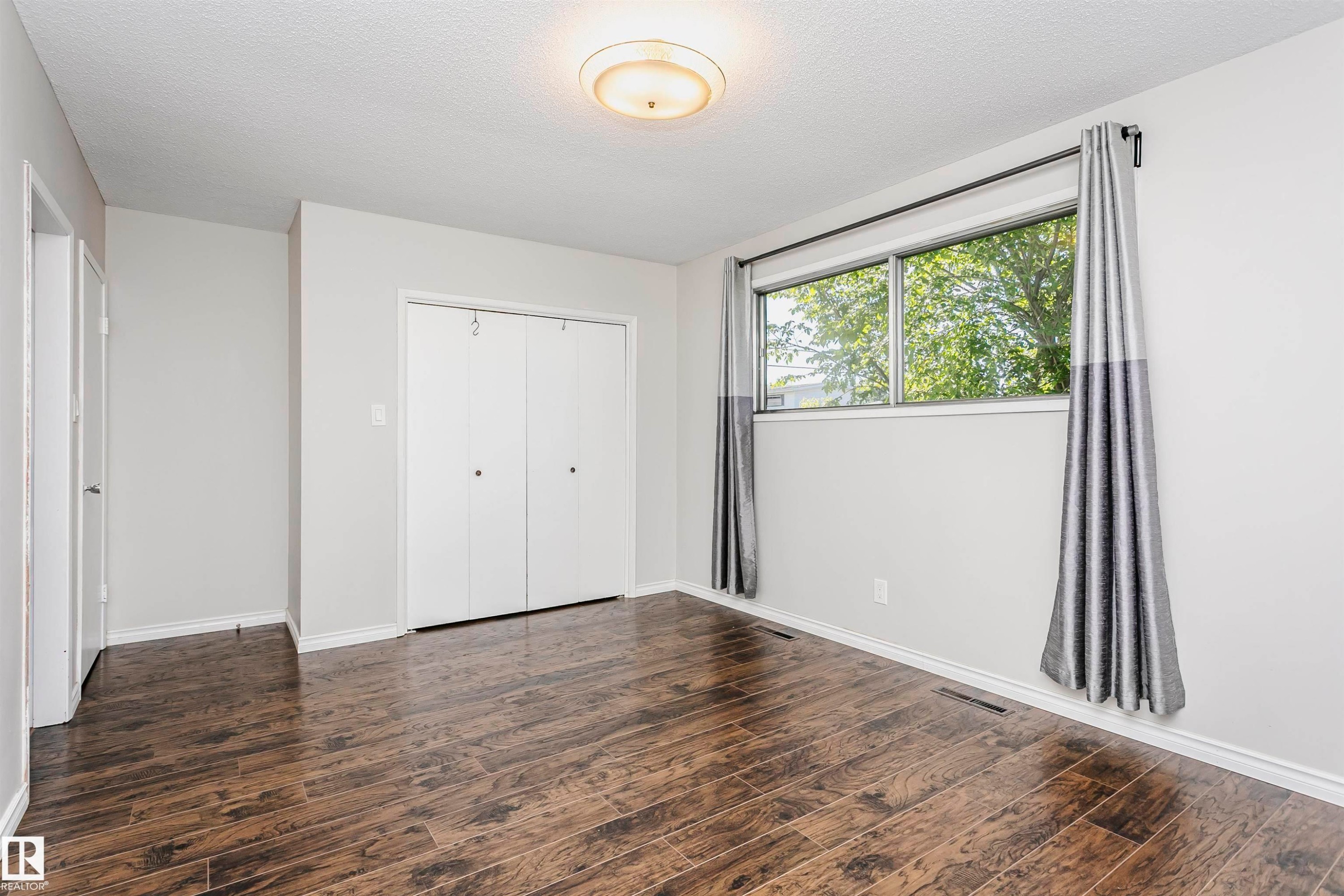 Wood-finish flooring, white walls, and a window with a dark rod - 11440 44A Avenue Nw, Edmonton, AB