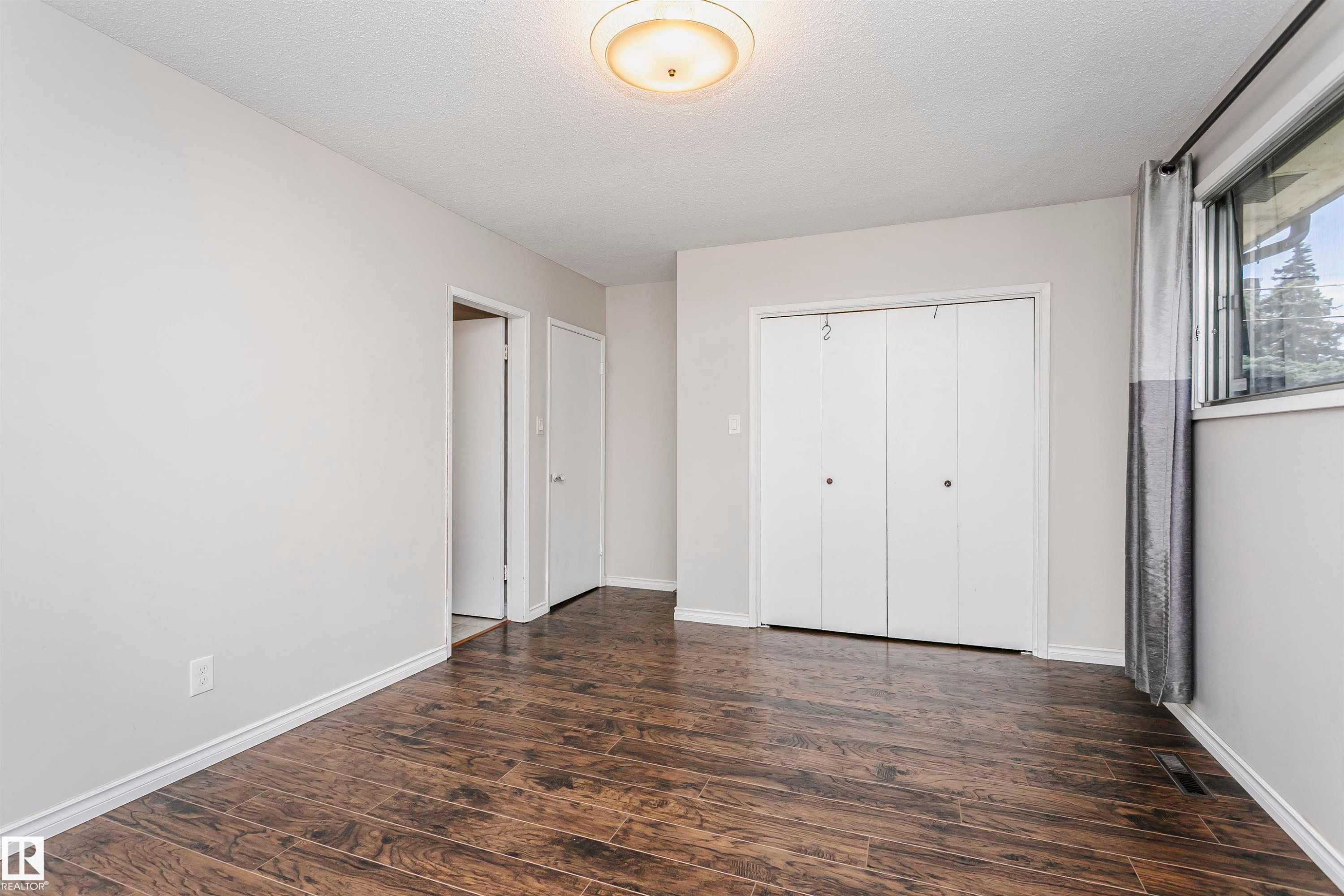 Wood-finish flooring, white walls, white trim, bi-fold closet doors, and an overhead light fixture - 11440 44A Avenue Nw, Edmonton, AB